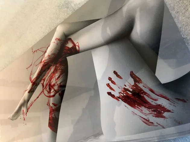 Photograph of a crumpled piece of paper with red paint streaks and splatters on its surface.