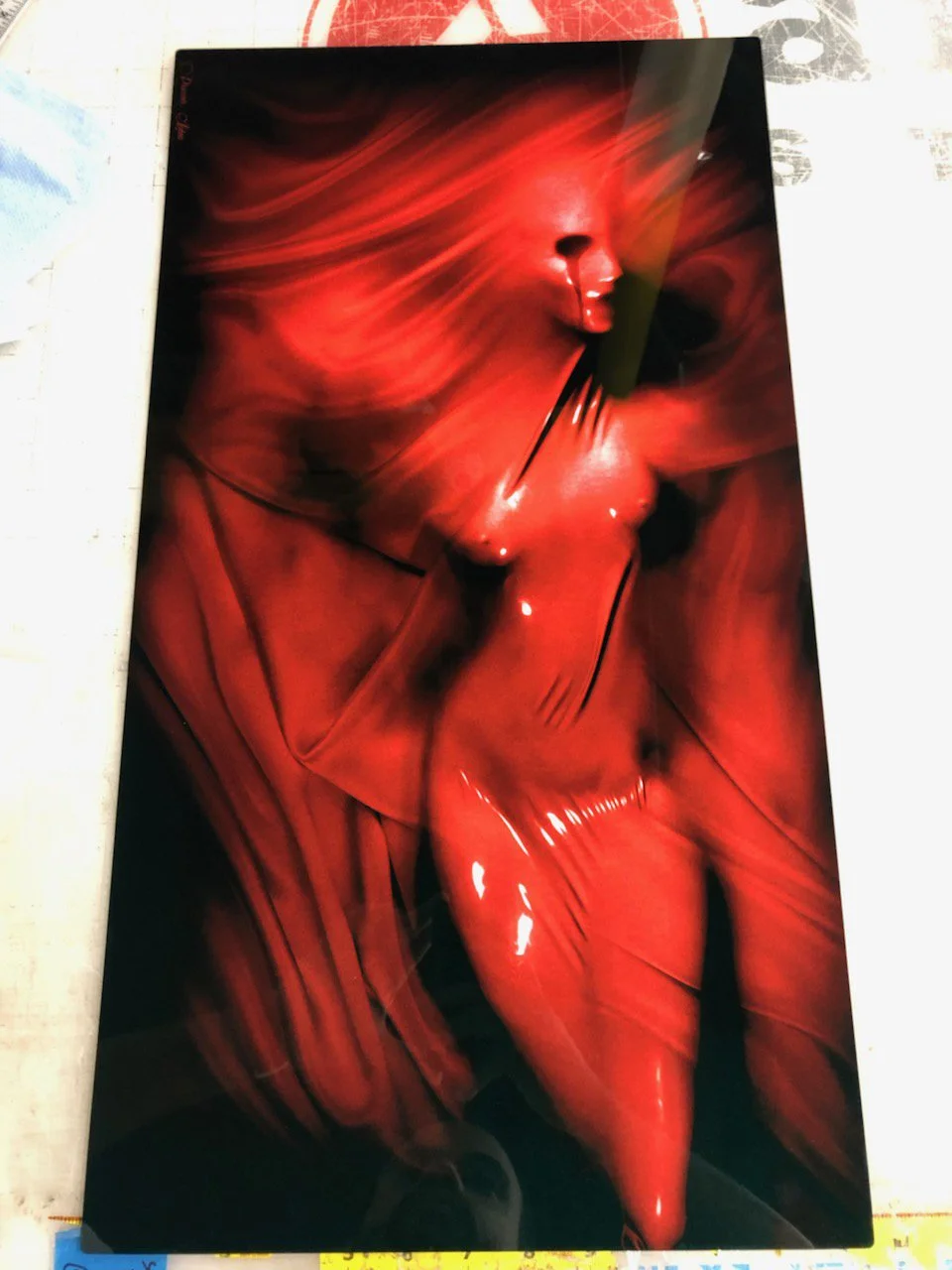 Artistic depiction of a nude female figure with a red, glossy, and abstract background. The figure's face is turned sideways, blending into the swirling red surroundings.