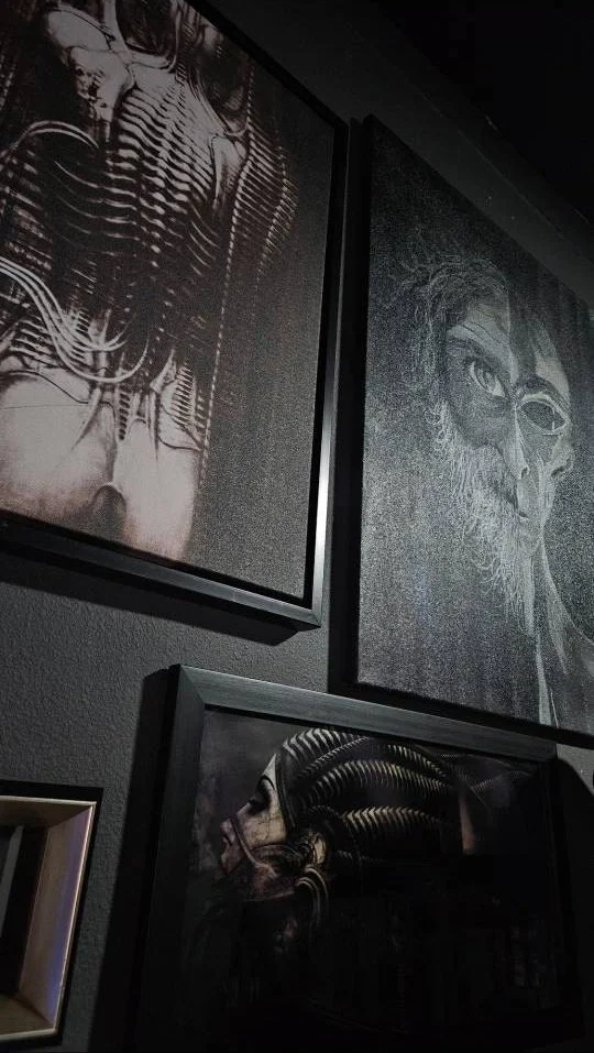 Dark-toned wall art featuring abstract human and animal skulls with intricate line work and metallic accents, displayed in black frames.