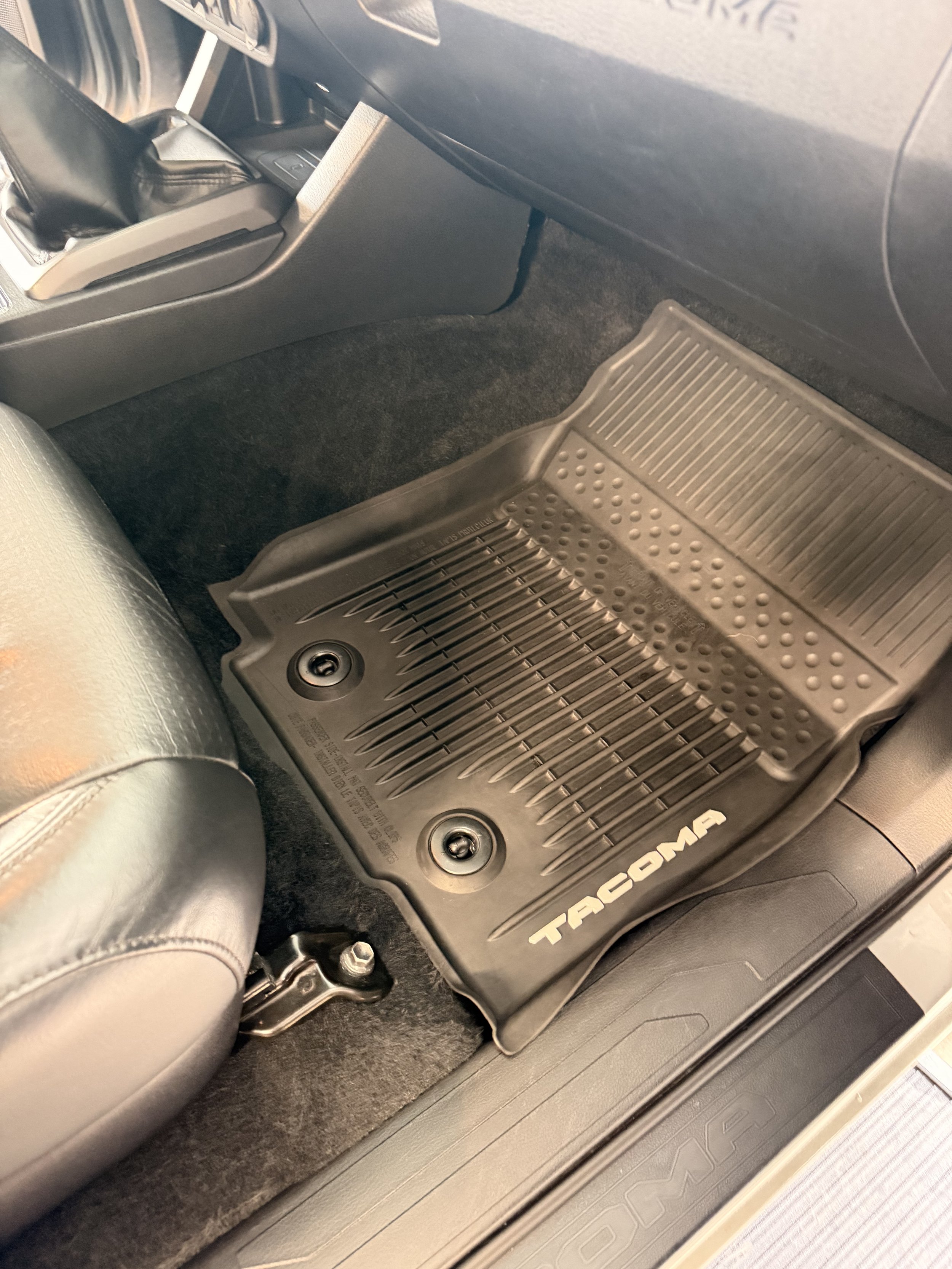 View of the driver seat area in a vehicle, showing a black floor mat with 