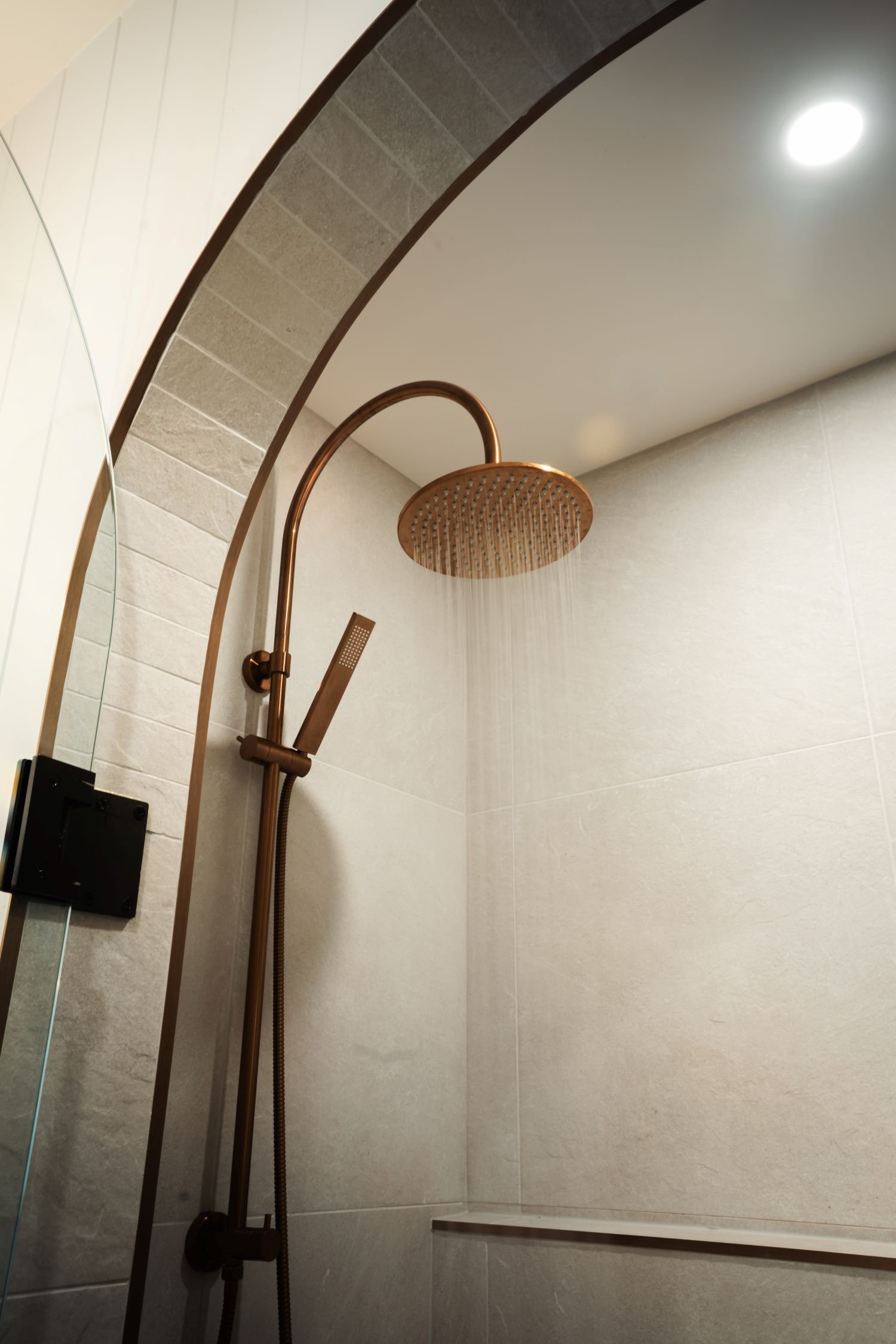 Arched copper shower fixture detail within the Raeburn ensuite.