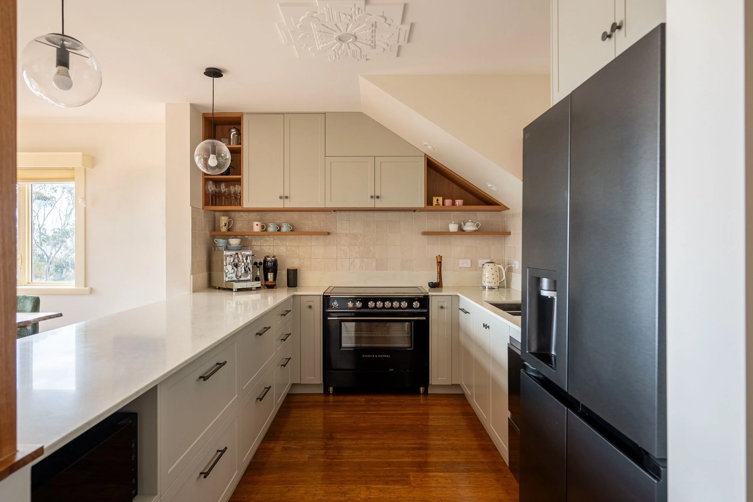 U-shaped kitchen with black freestanding cooker, timber floors and open shelving