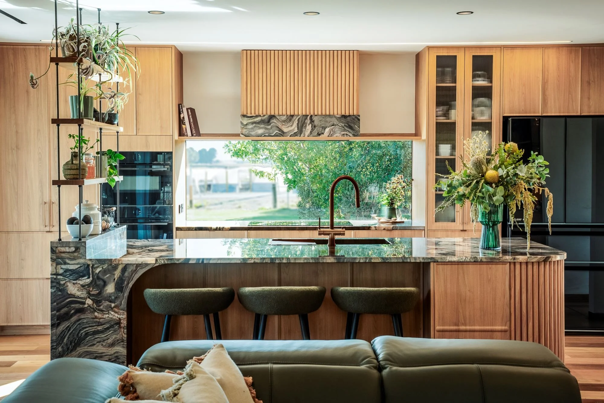 Open plan kitchen at Raeburn with timber cabinetry, dramatic stone island bench and large picture window overlooking the landscape.