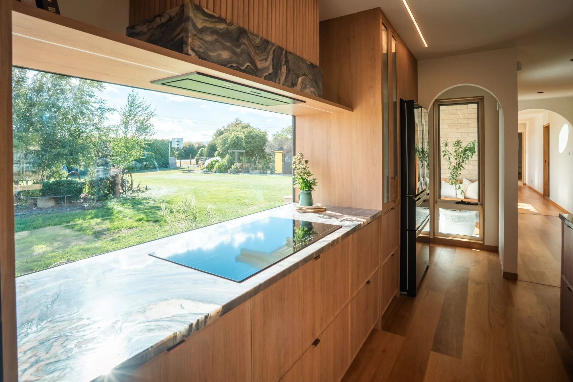 Kitchen bench at Raeburn positioned beneath a large horizontal window framing views of the surrounding Tasmanian landscape.