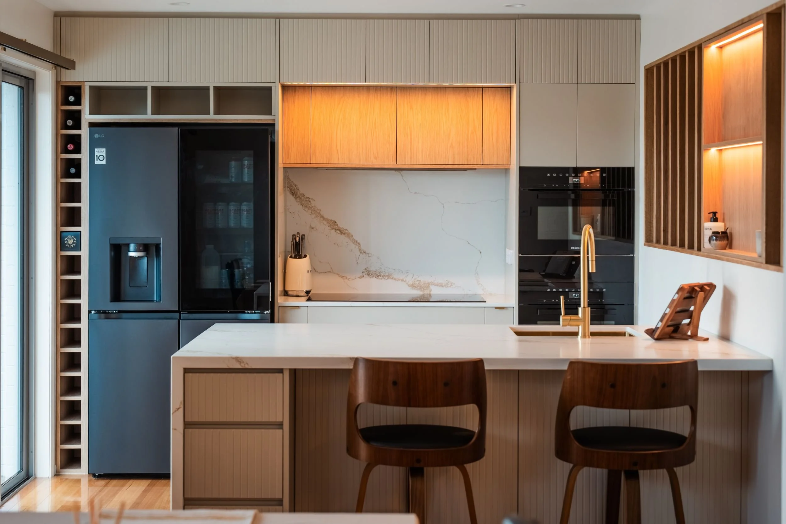 Light, modern kitchen with oak-look overhead cabinets, stone splashback, waterfall island and timber stools, Norwood Tasmania
