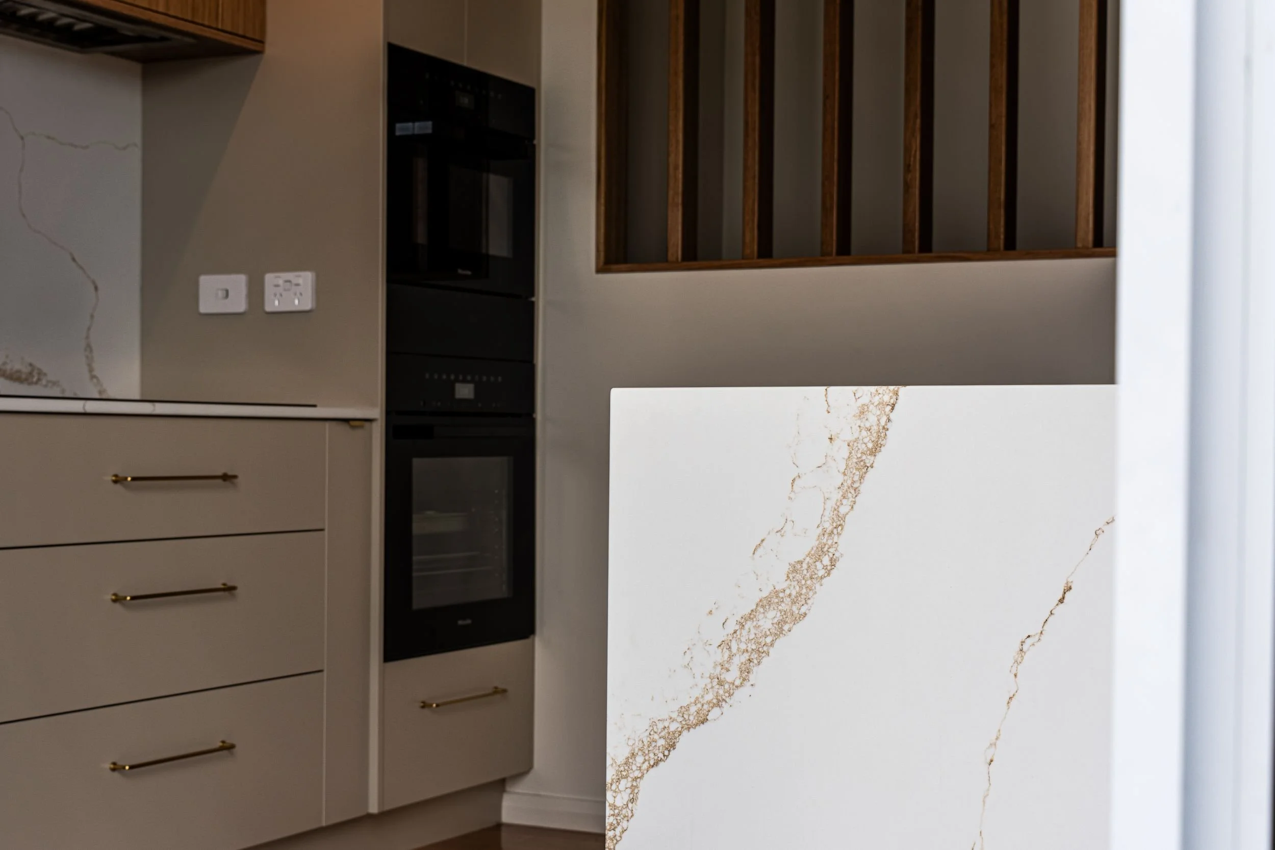 Close-up of veined stone waterfall end and oak-look joinery