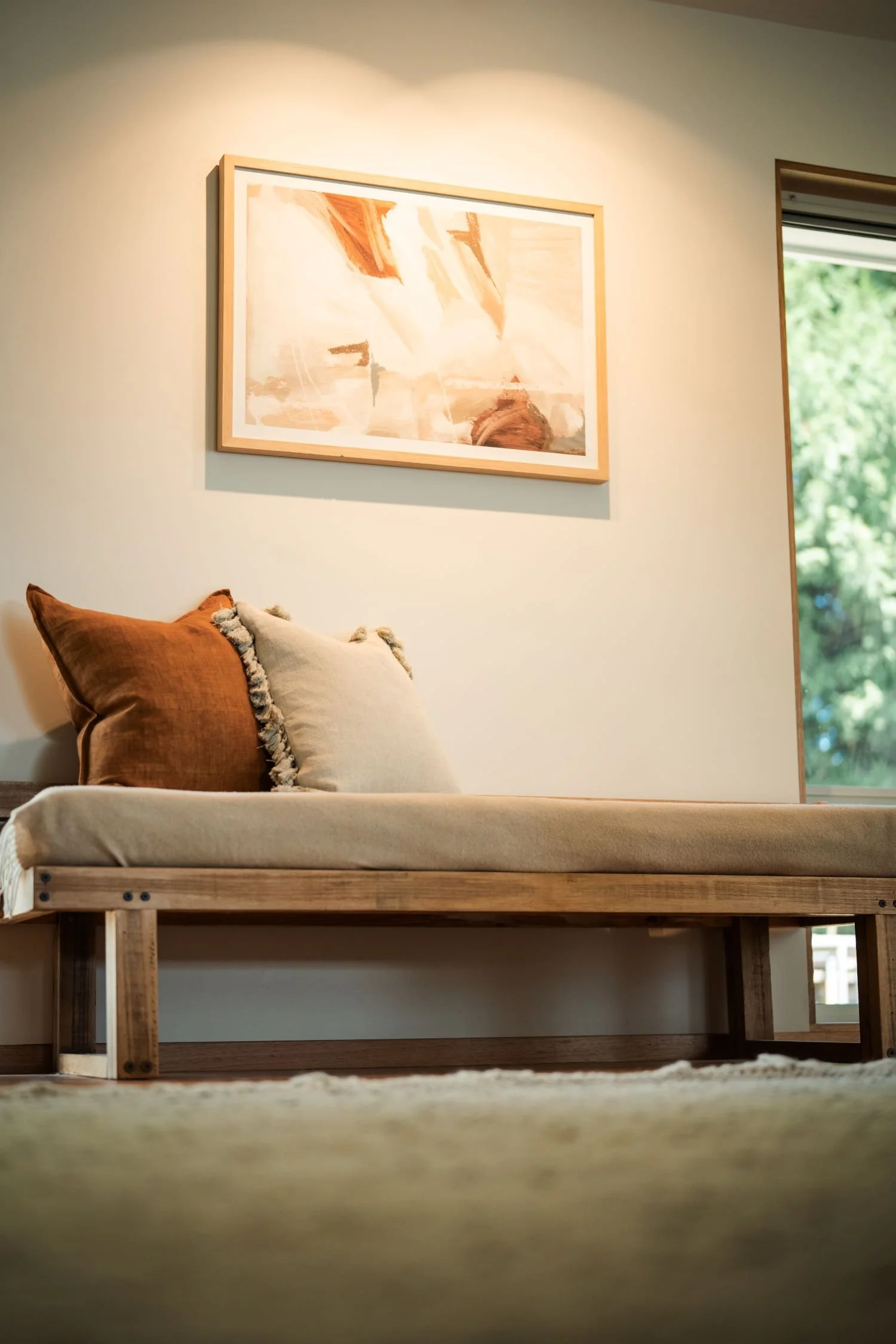 Window seat with layered cushions and natural light in the Raeburn living area.