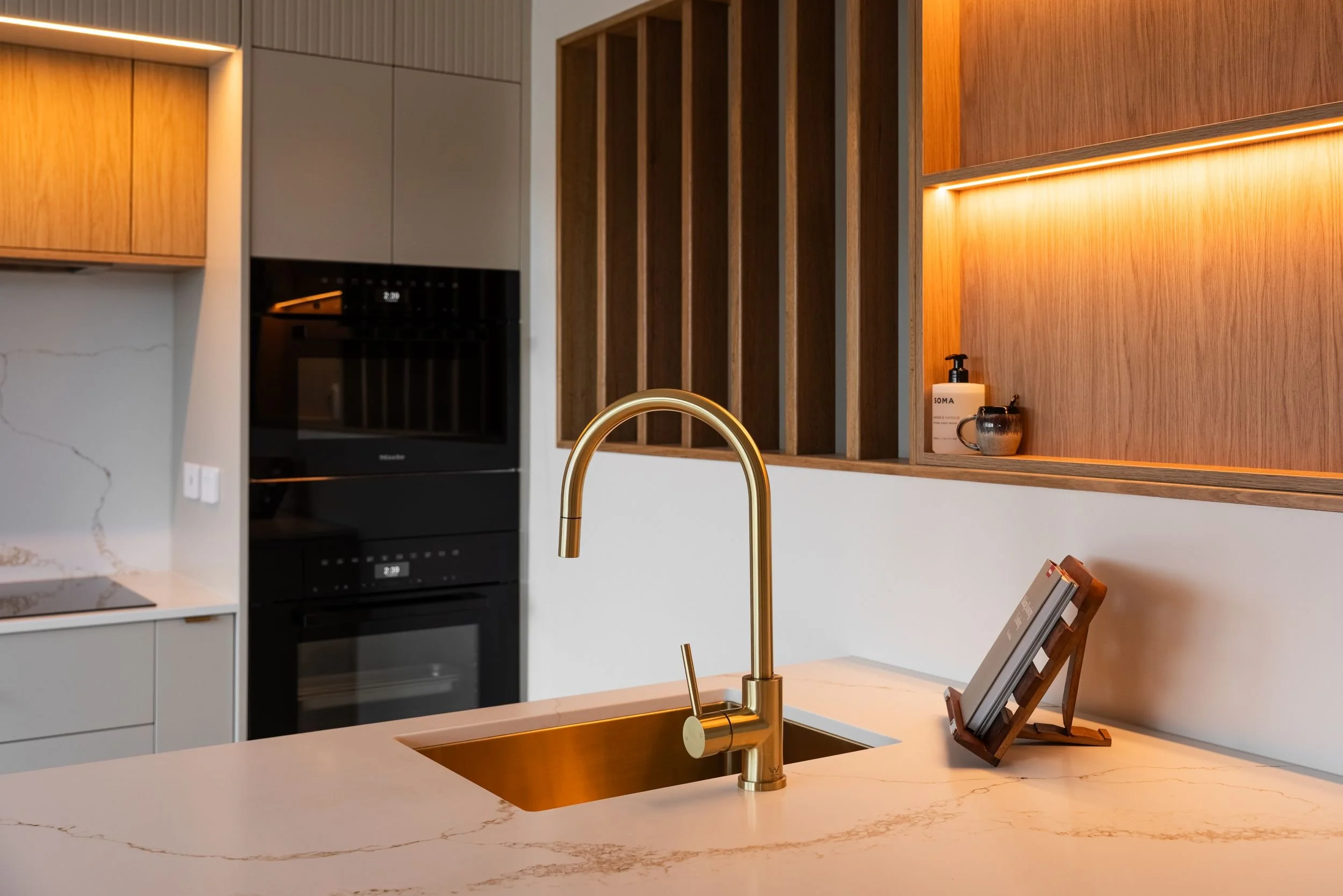 Brass sink and tapware set into a white stone benchtop