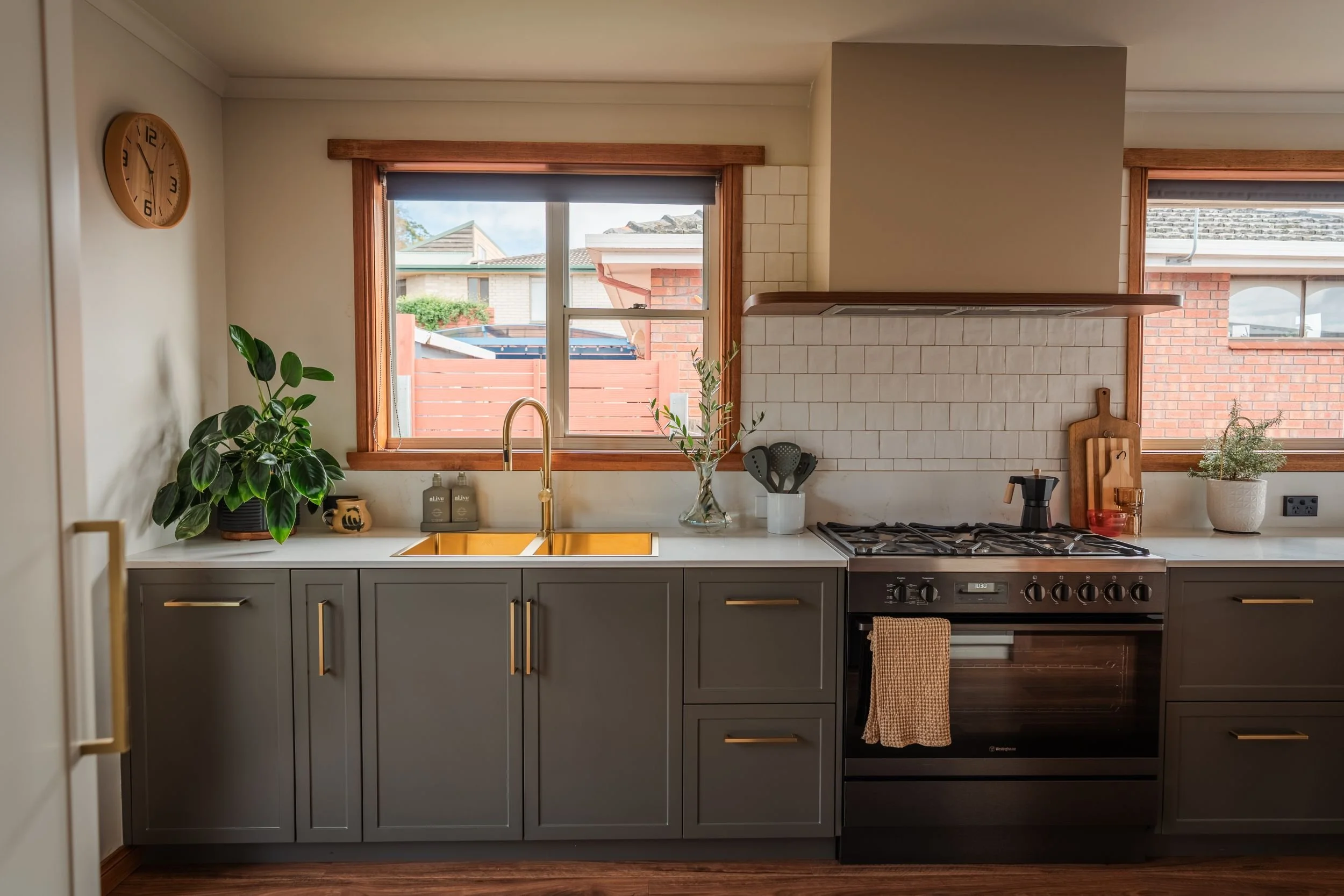 Cooking wall with gas cooktop, brass tapware, white subway tiles and timber-framed windows