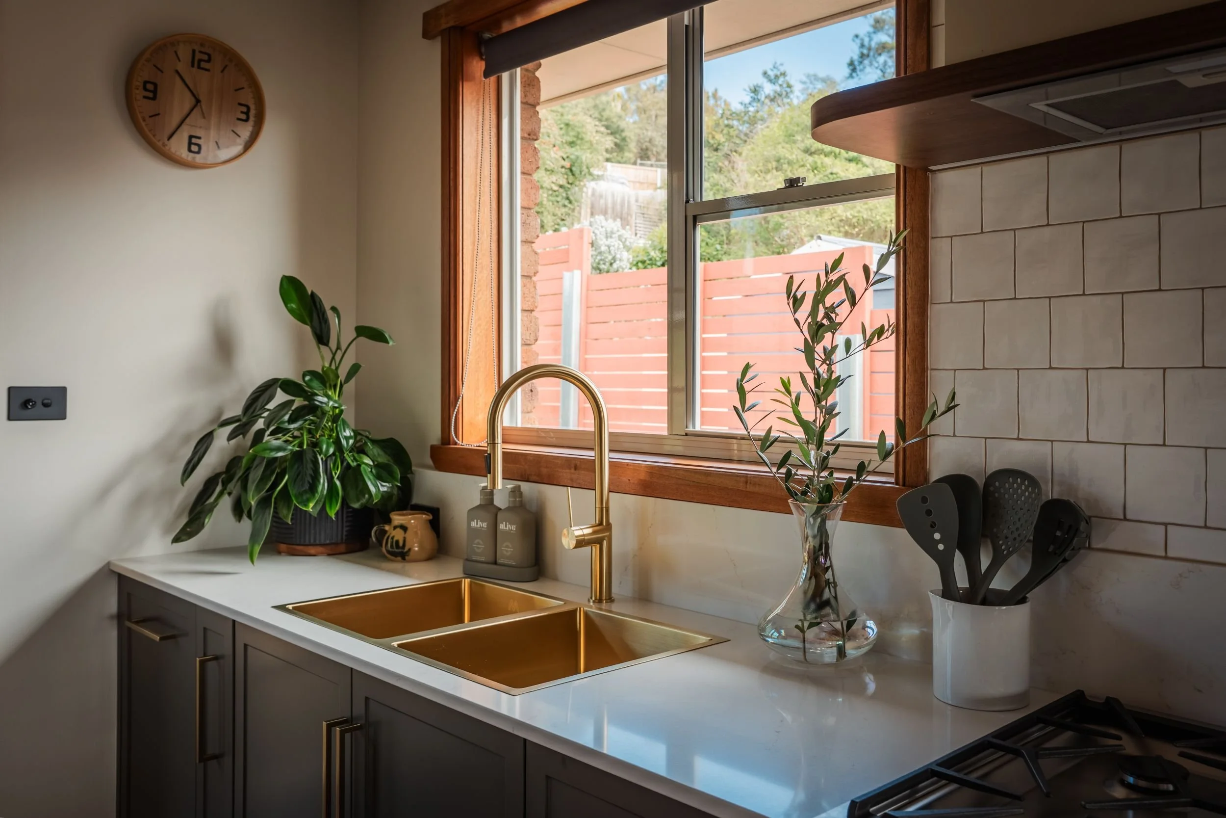 Brass double sink and gooseneck tap under a timber-framed window