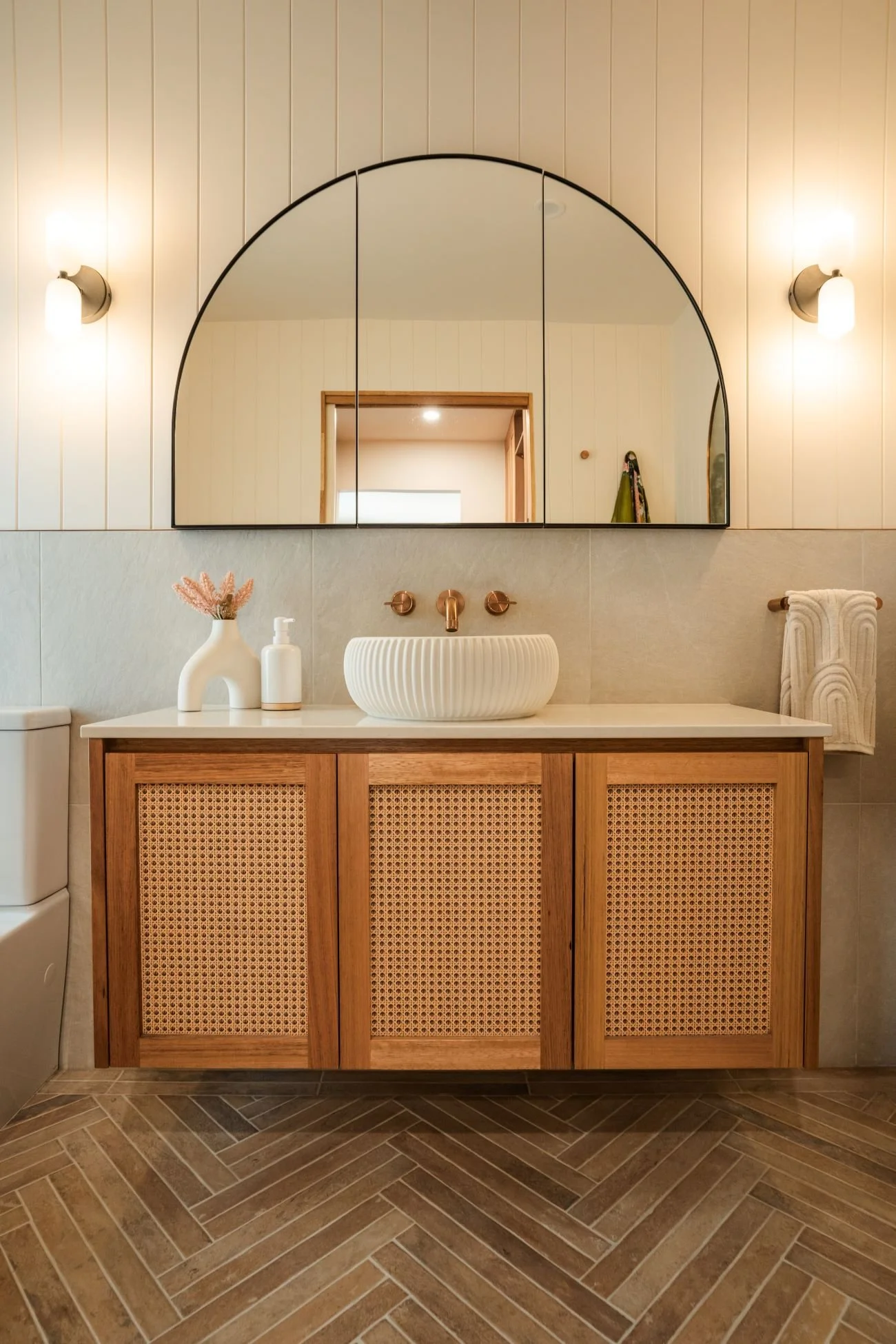 Ensuite vanity at Raeburn with timber cabinetry, rattan joinery panels and concrete basin.
