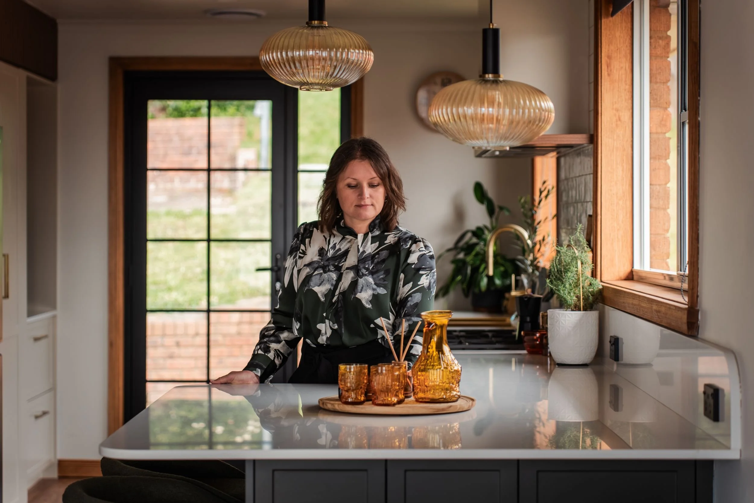 Building and interior designer Tahleah Hoyle at the island bench of a Riverside kitchen she designed