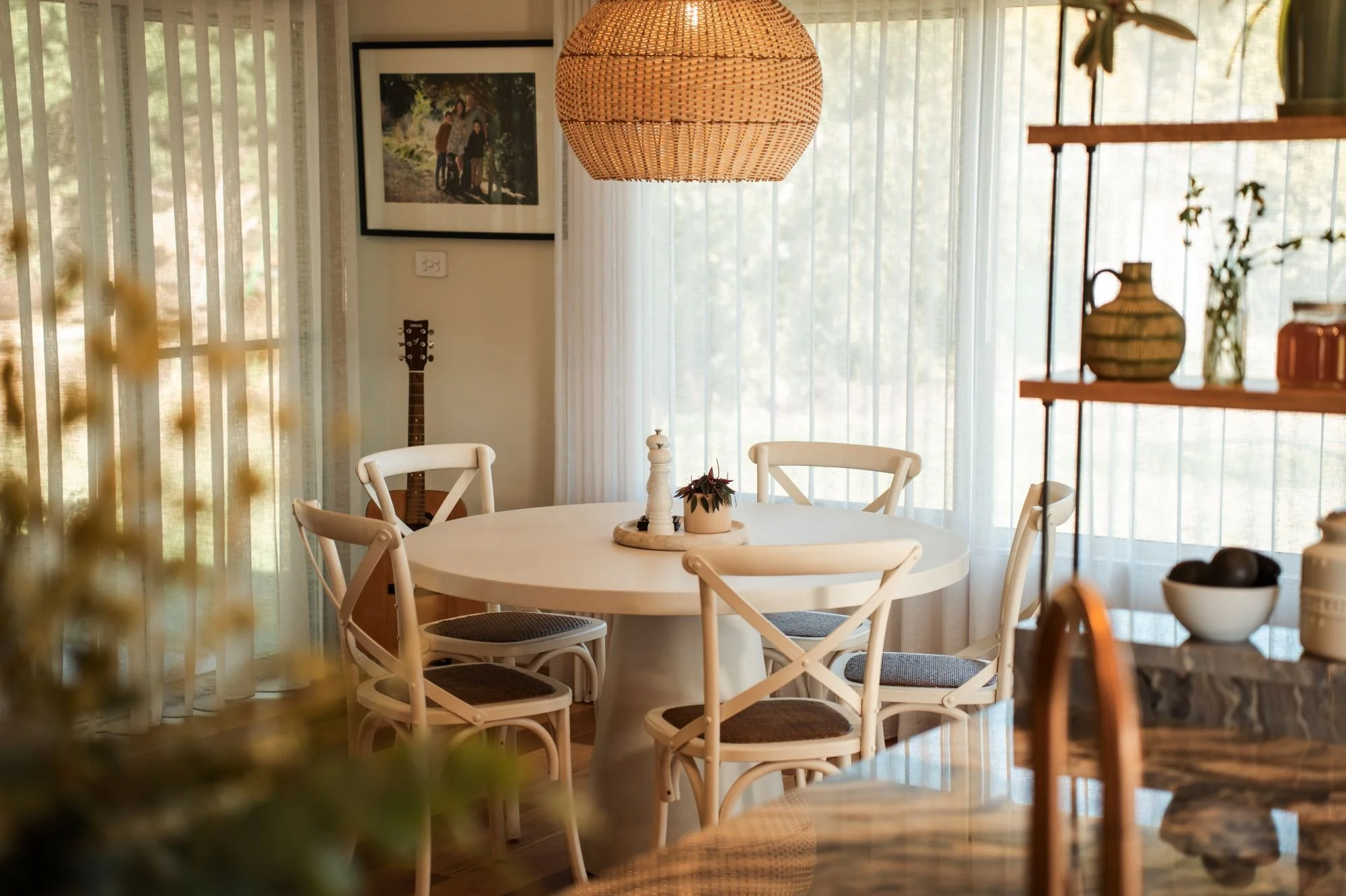 Dining area at Raeburn featuring soft natural light, sheer curtains and timber details.