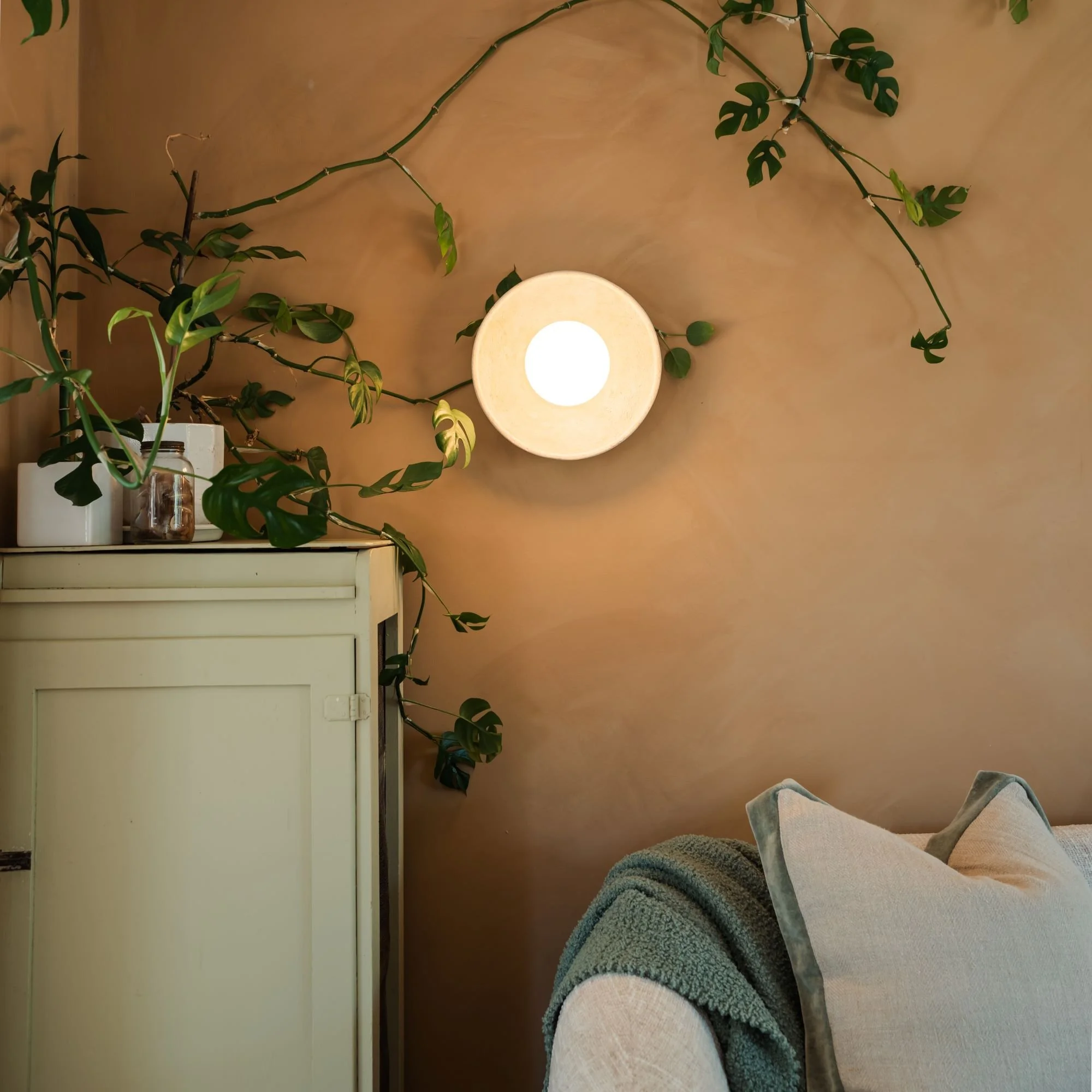 Sitting room styling with warm lighting, limewash, greenery and natural finishes