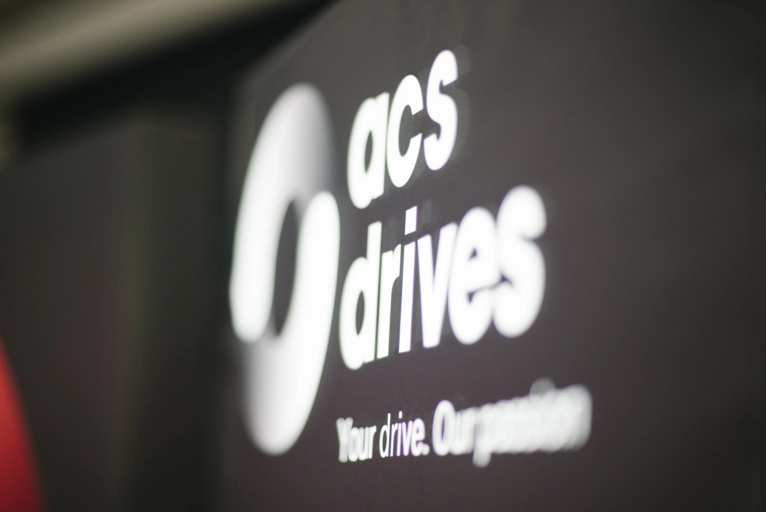 A close-up of a sign for a DOCS drive-thru with the company's logo and slogan 'Your drive. Our passion.'