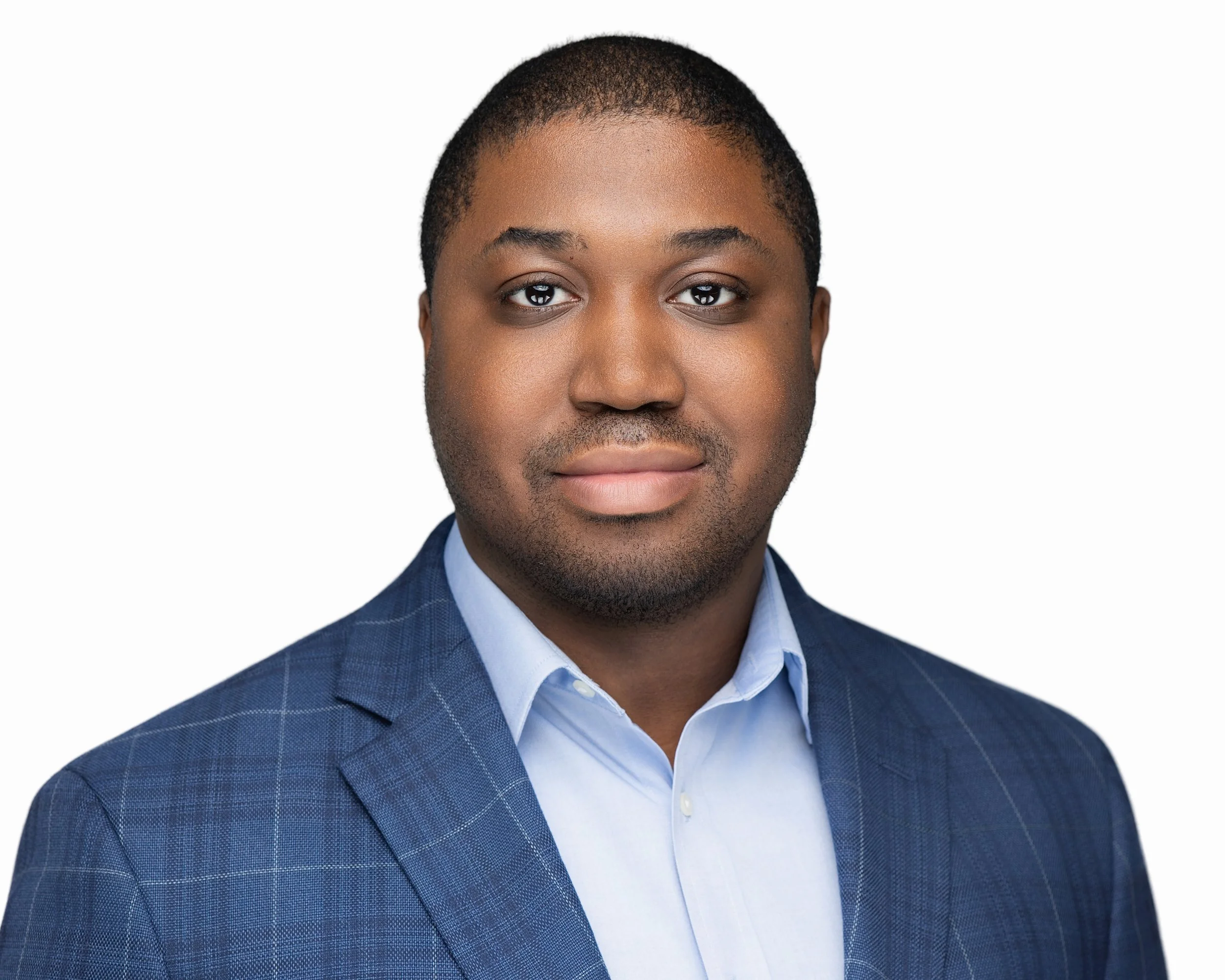 Portrait of a man in a blue checkered suit and light blue collared shirt against a white background.