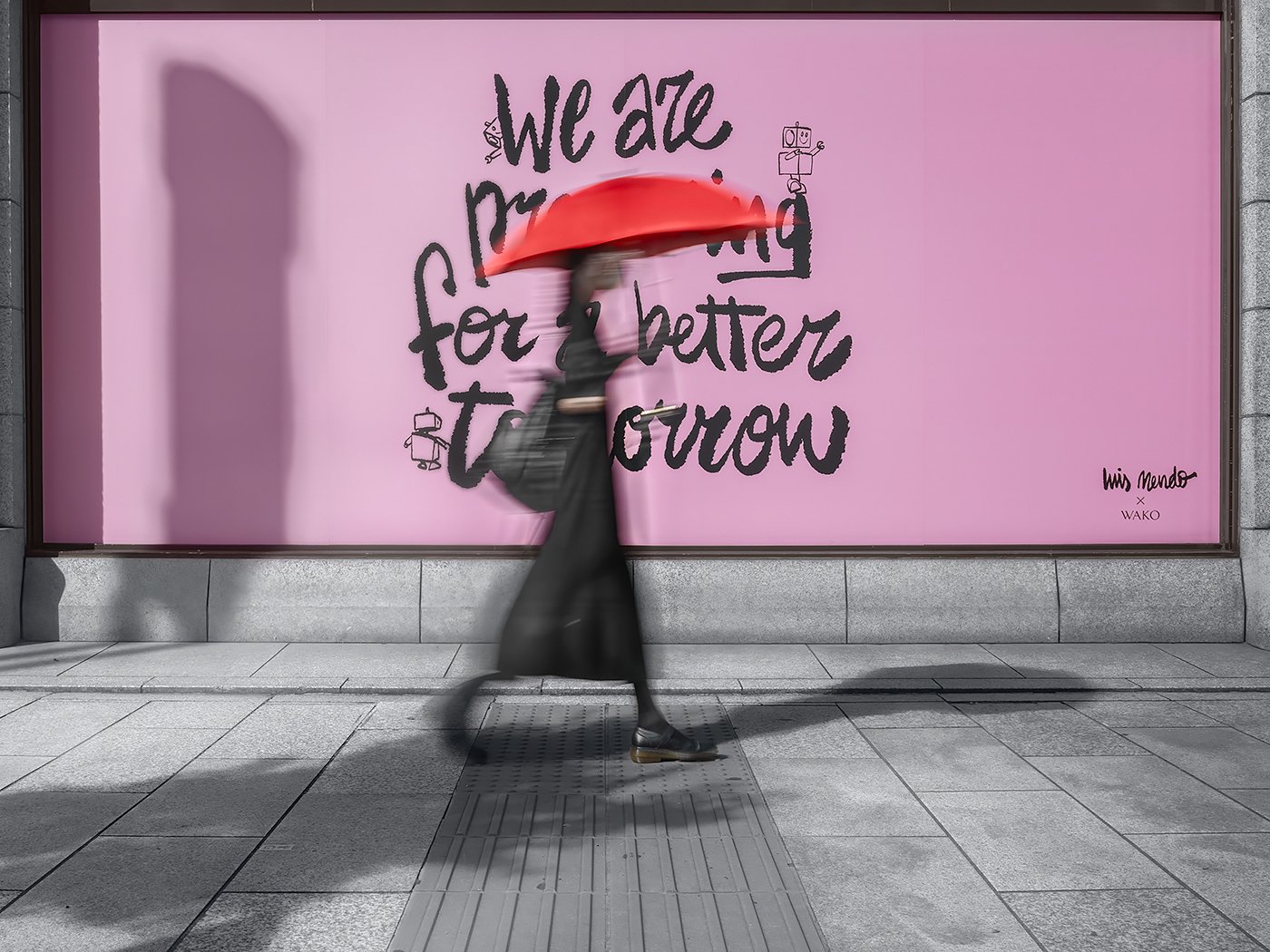 Motion-blurred woman in a black dress carrying a red umbrella walking past a pink storefront window with large black lettering reading “We are … for a better tomorrow".