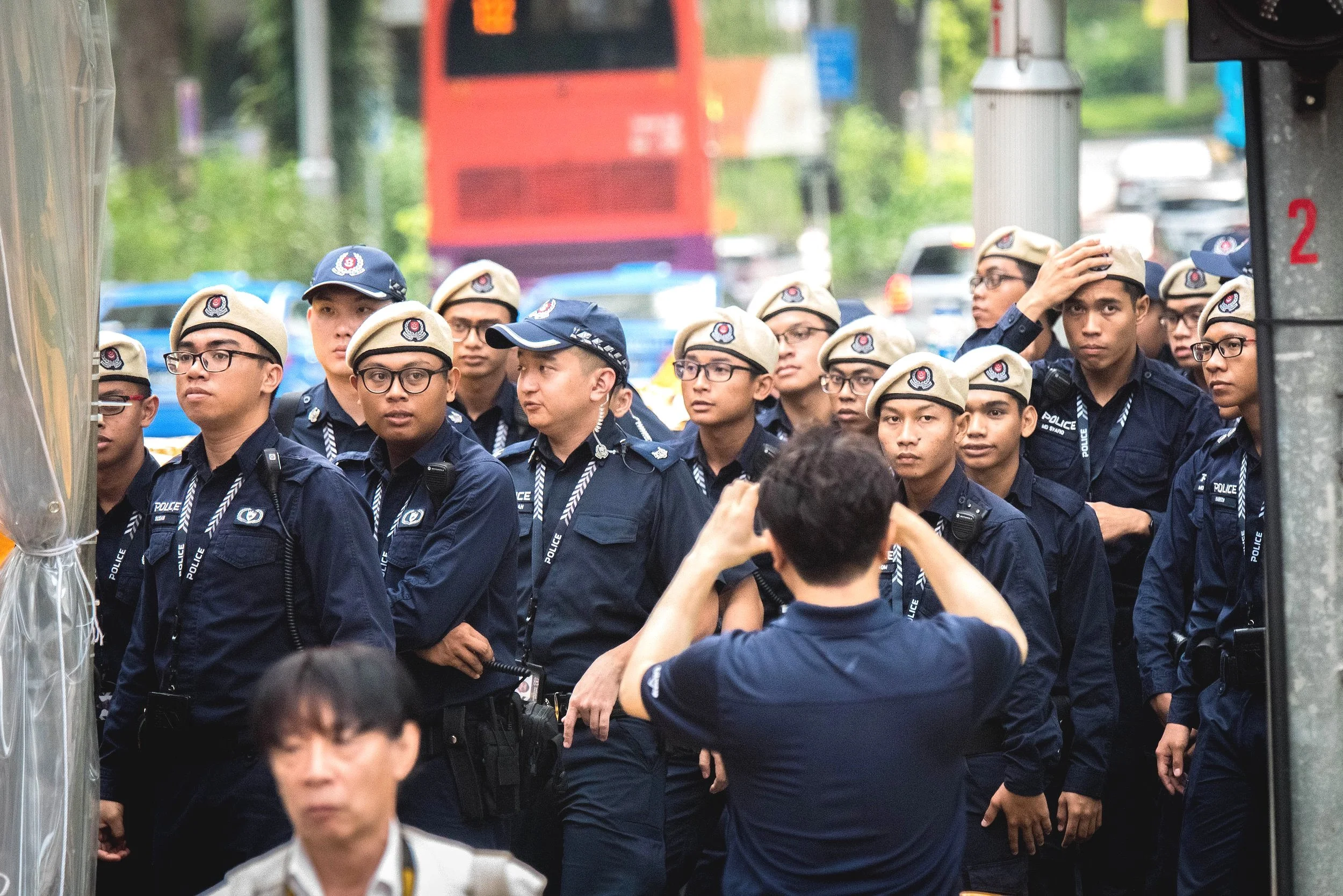 A South Korean journalist snapping a photo of the Singapore Police Force officers on standby while awaiting the arrival of North Korean supreme leader Kim Jong-un outside the vicinity of St. Regis hotel for the 2018 North Korea–United States Singapor