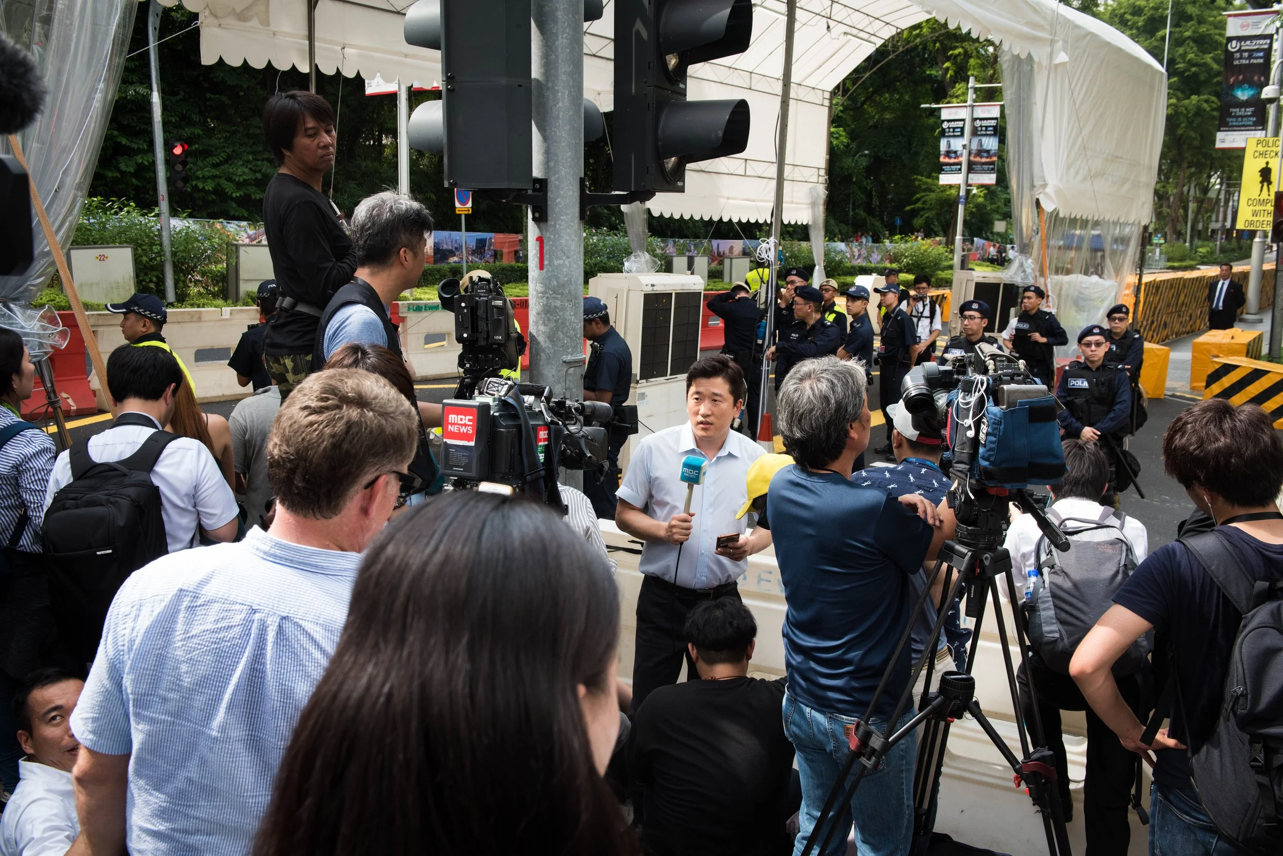 A South Korean journalist makes do with the limited shared space to go on recording while they await the arrival of North Korean supreme leader Kim Jong-un outside the vicinity of St. Regis hotel on 10 June, 2018.