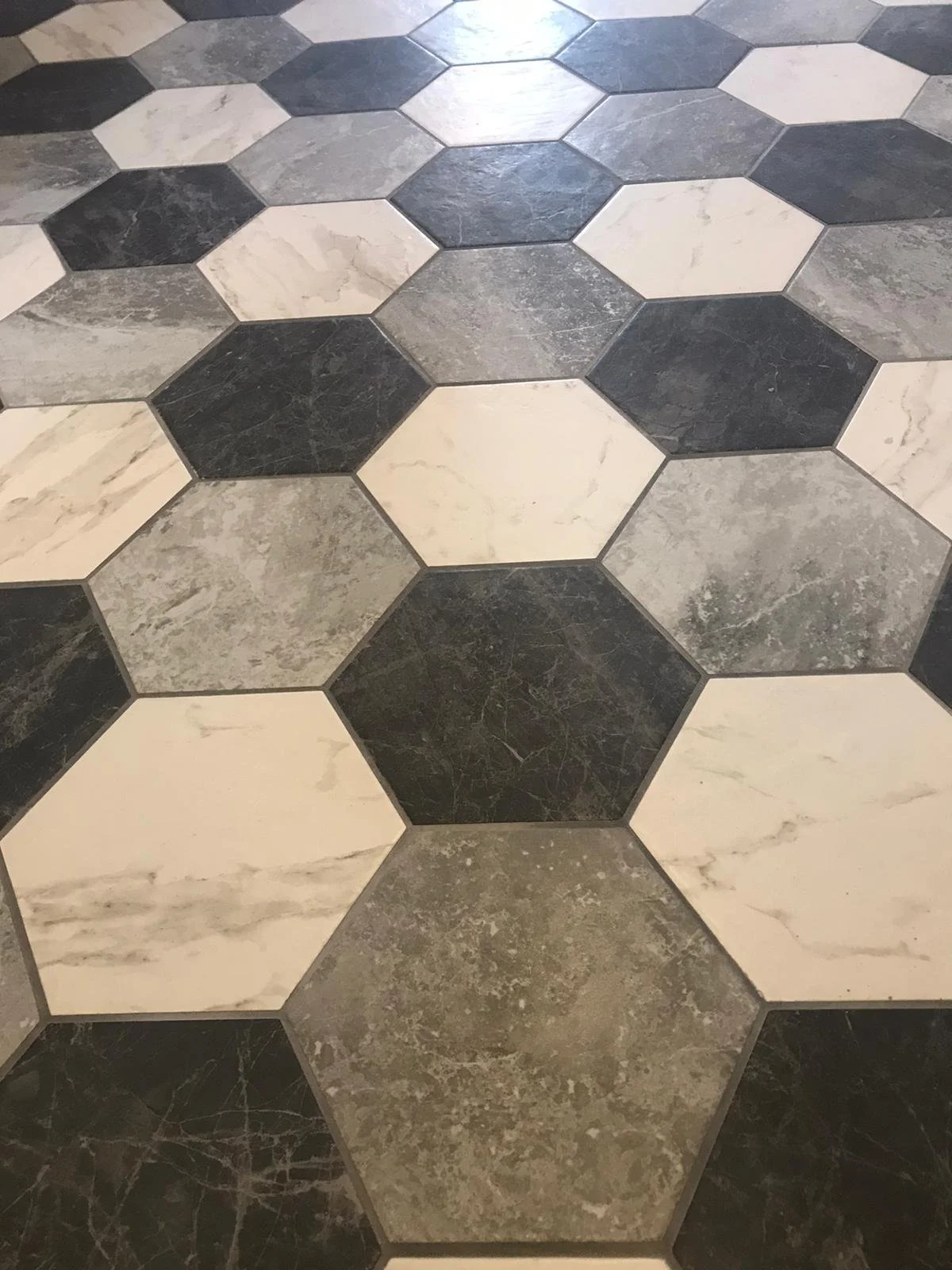 Hexagonal black, white, and grey patterned floor tiles.