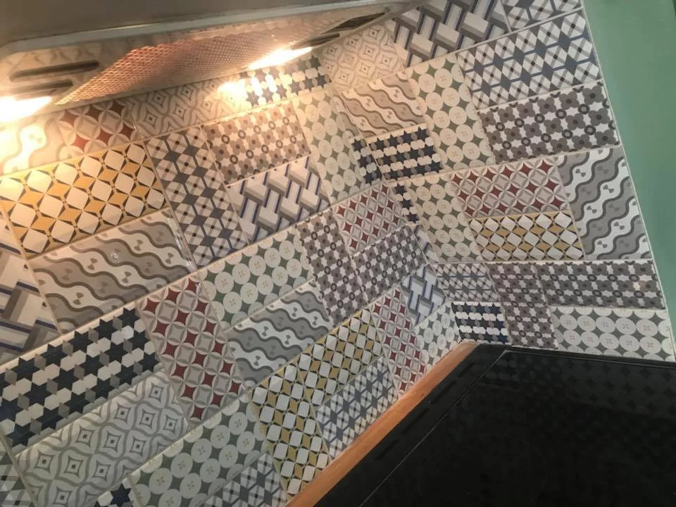 Kitchen backsplash with colorful patterned tiles and induction cooktop.