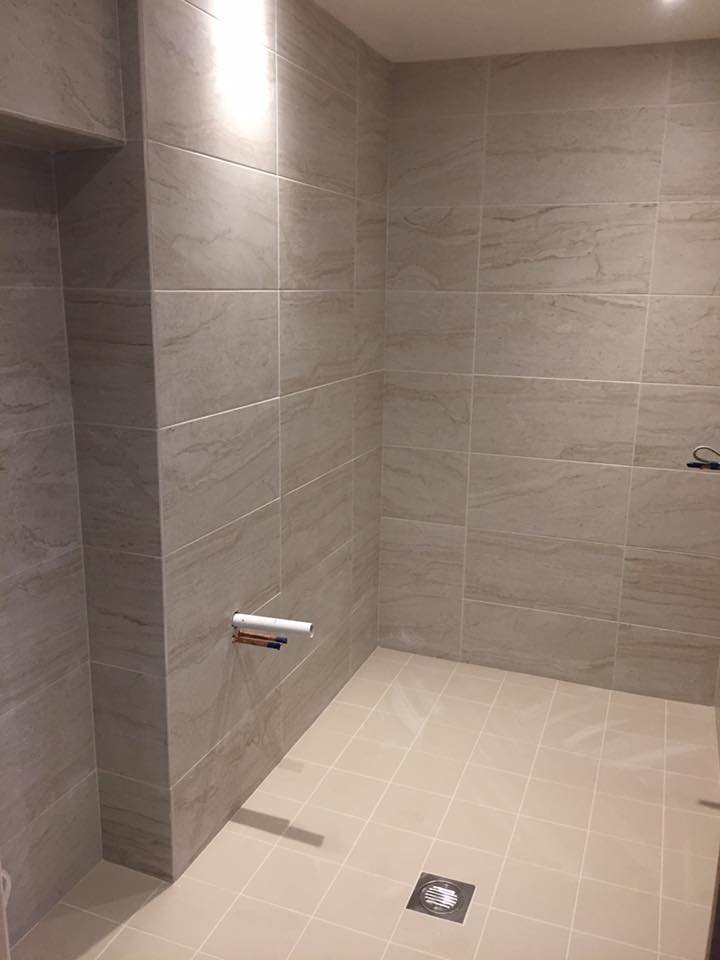 empty bathroom with tiled walls and floor, toilet paper holder without paper