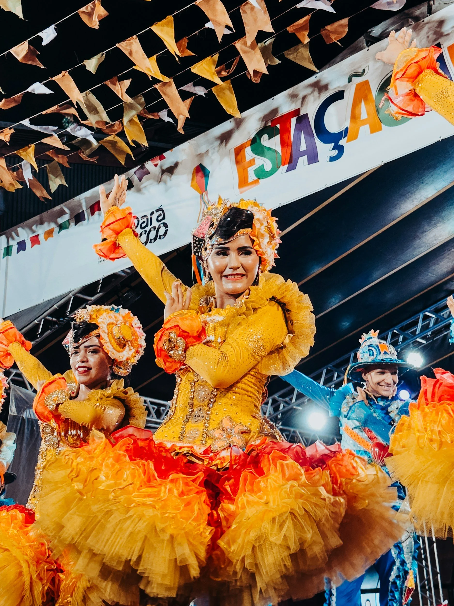 Night scene at a music event with a crowd of people, colorful neon sign reading "Montreux Jazz Festival" and lush greenery around.