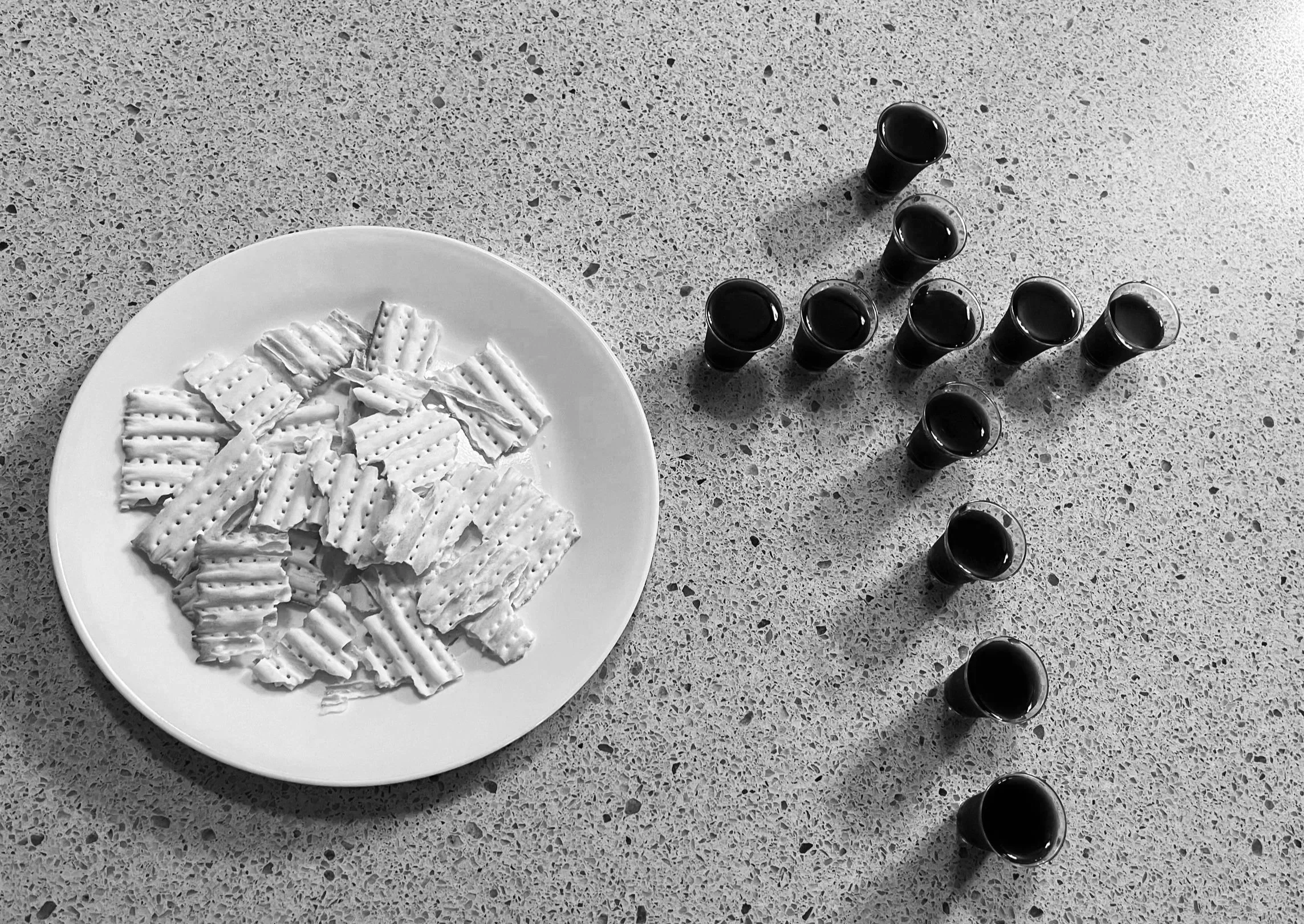 Communion glasses filled with juice and crackers rest on marble counter