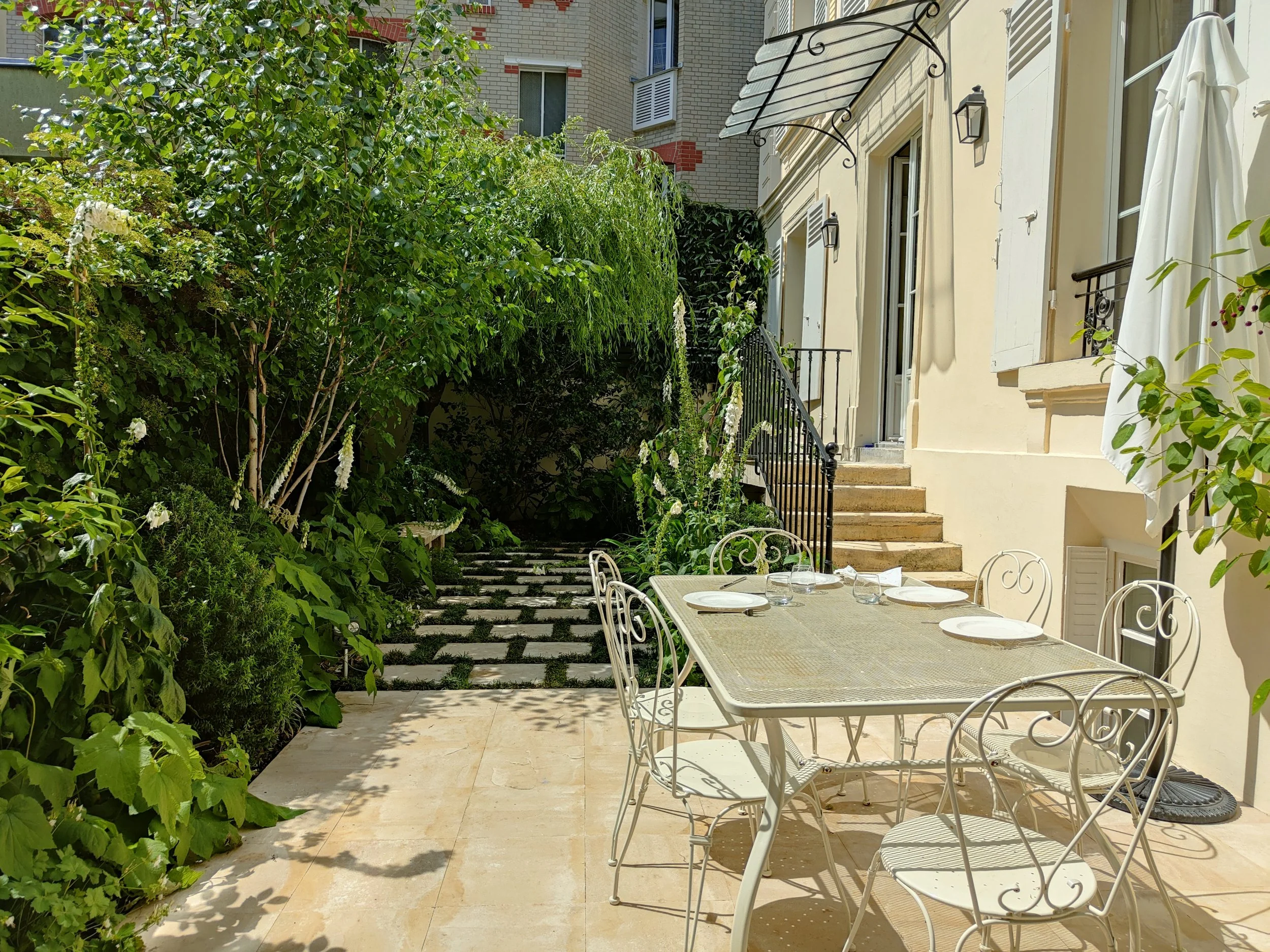 Aménagement de jardin de ville à Paris, avec terrasse, dallage en pierre et palette végétale dense