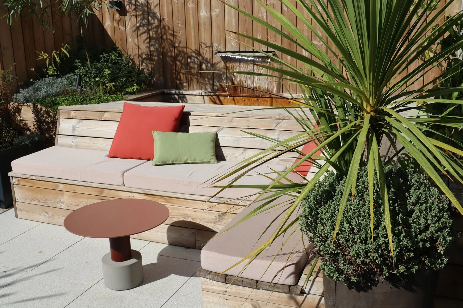 Terrasse paysagère à Paris avec banquette en bois, plantes en bacs, palmier et espace salon extérieur.