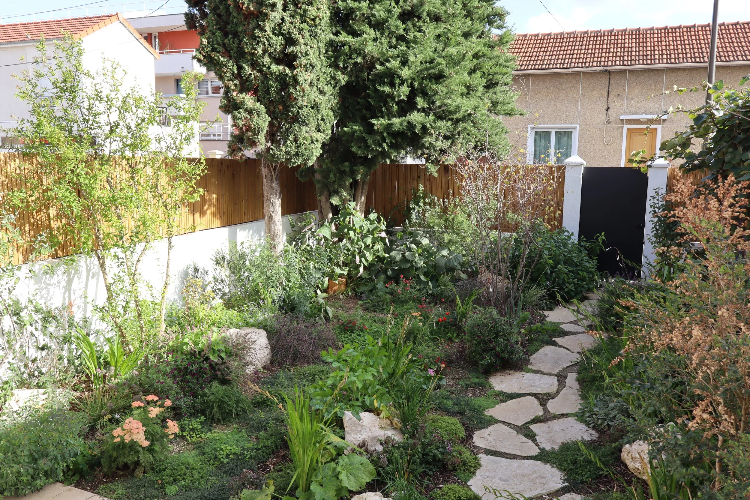 Aménagement paysager d'un jardin de ville privé avec cheminement minéral, brise-vue en bois et végétation luxuriante par Simonson Landscape.