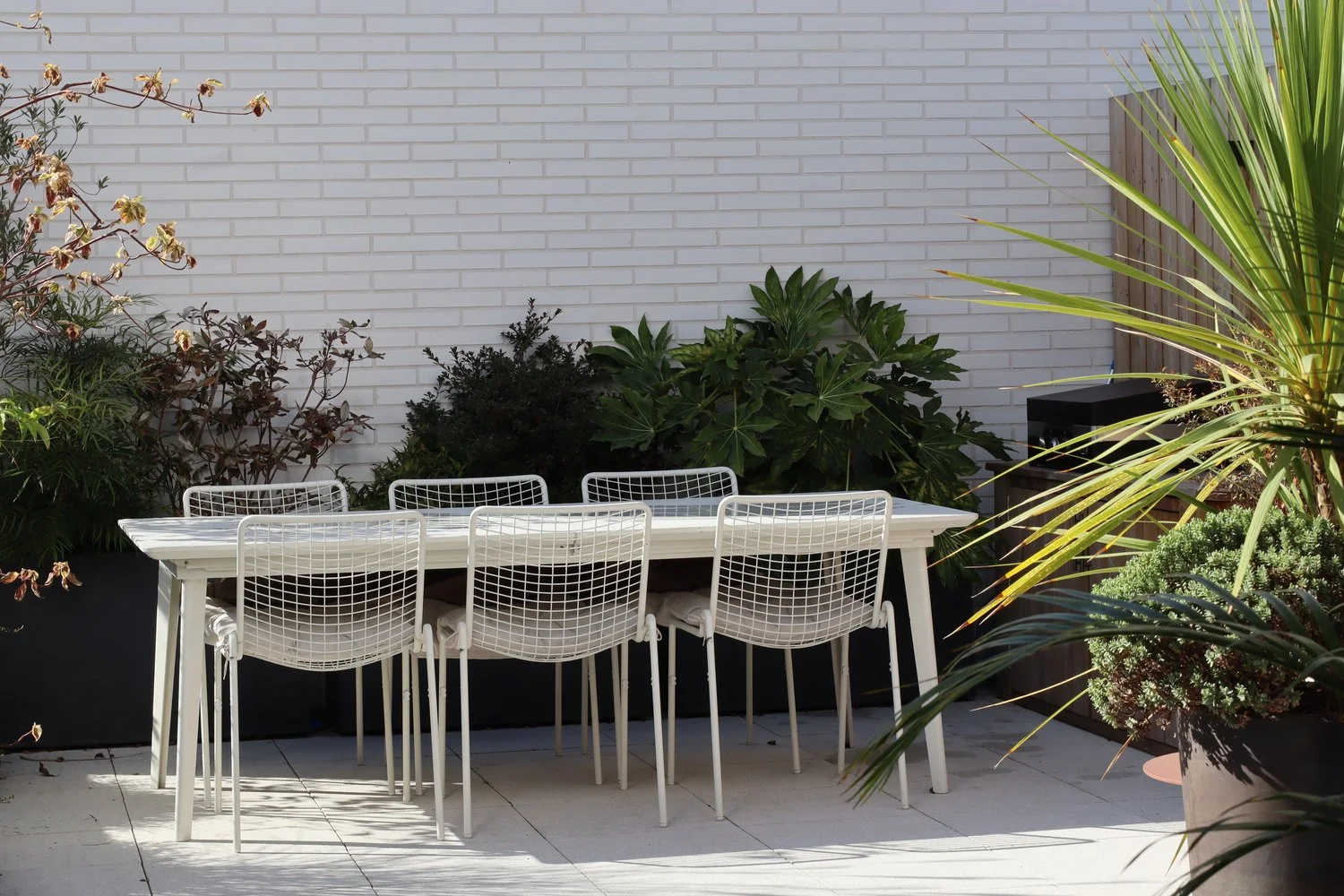 Chaises et table blanches, dans un jardin et une terrasse contemporains