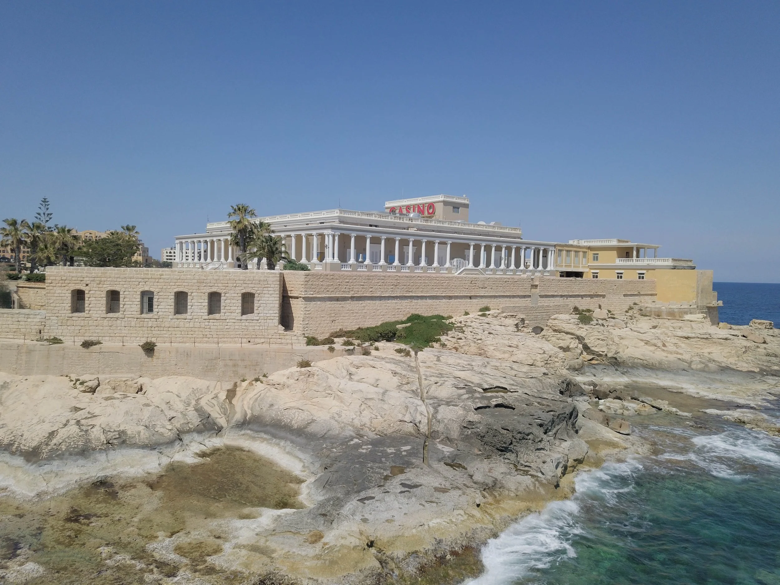 Palais sur la côte rocheuse de Malte, architecture historique en pierre face à la mer, contexte patrimonial et paysages littoraux.