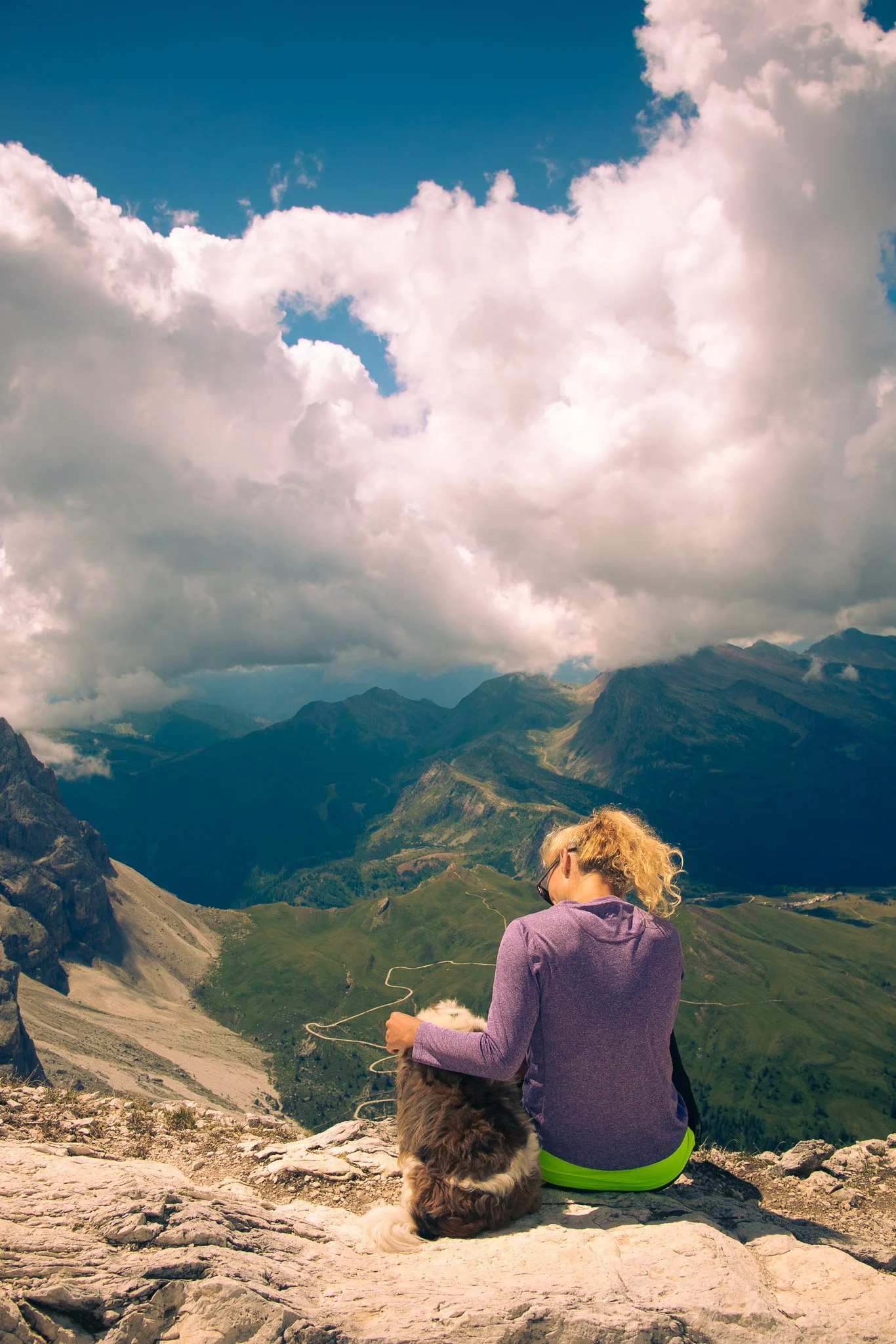 Woman comforting her exhausted dog on a mountain top
