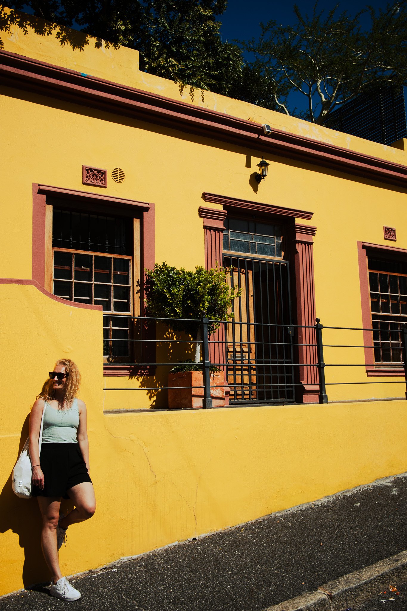 Woman leaning onto a bright yellow wall smiling
