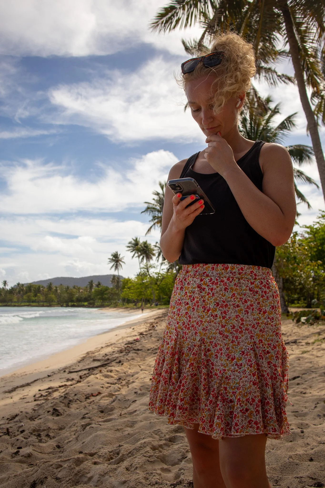 Woman thinking while looking at her Iphone with a tropical background