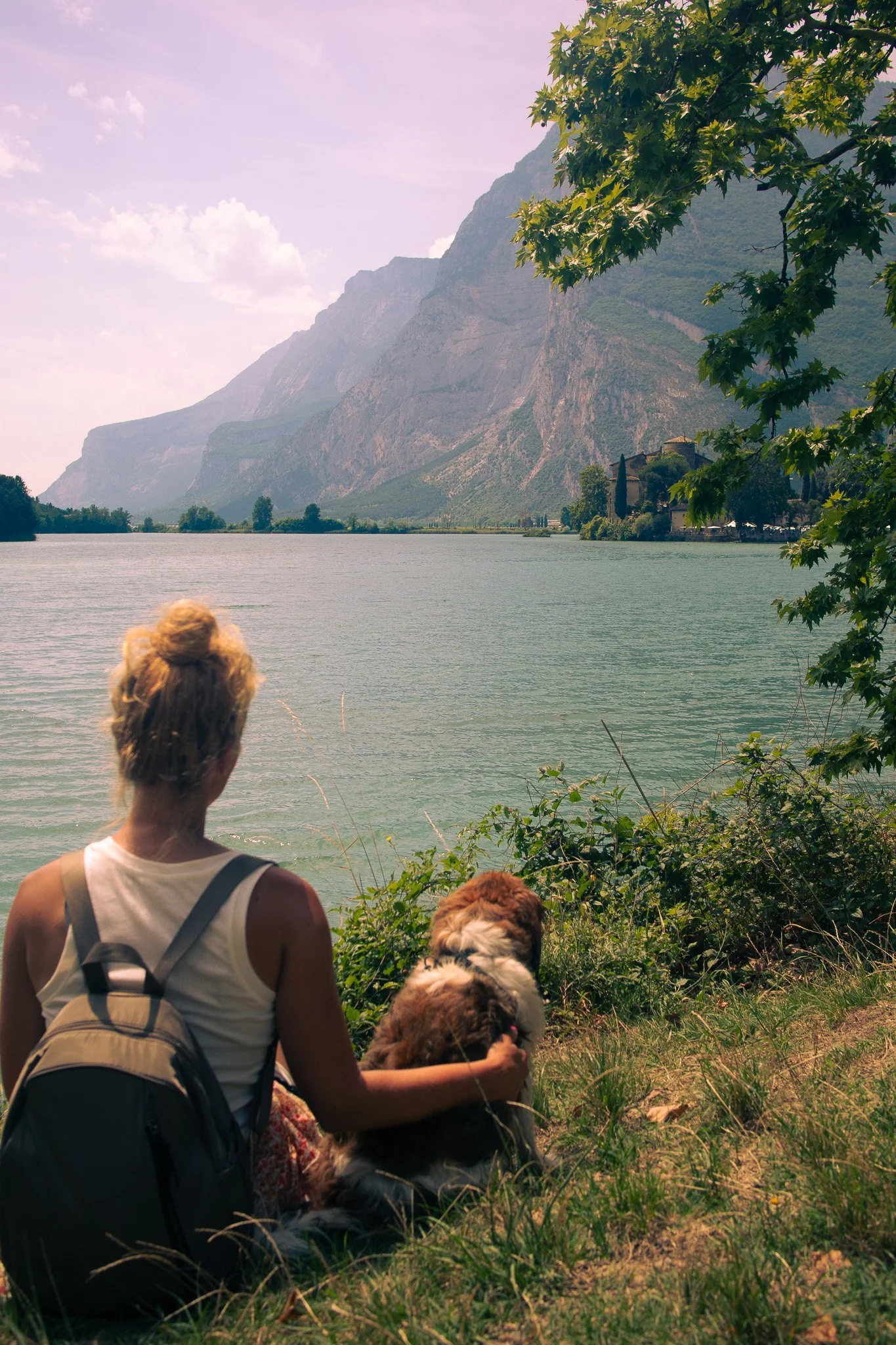 Woman sitting with her dog looking out on an Italian lake