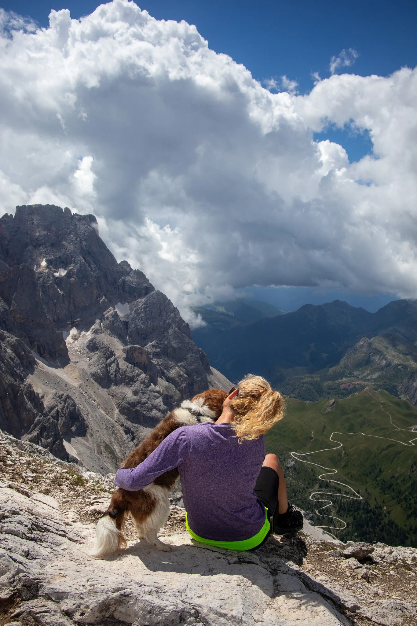 Woman comforting a dog on a mountain top