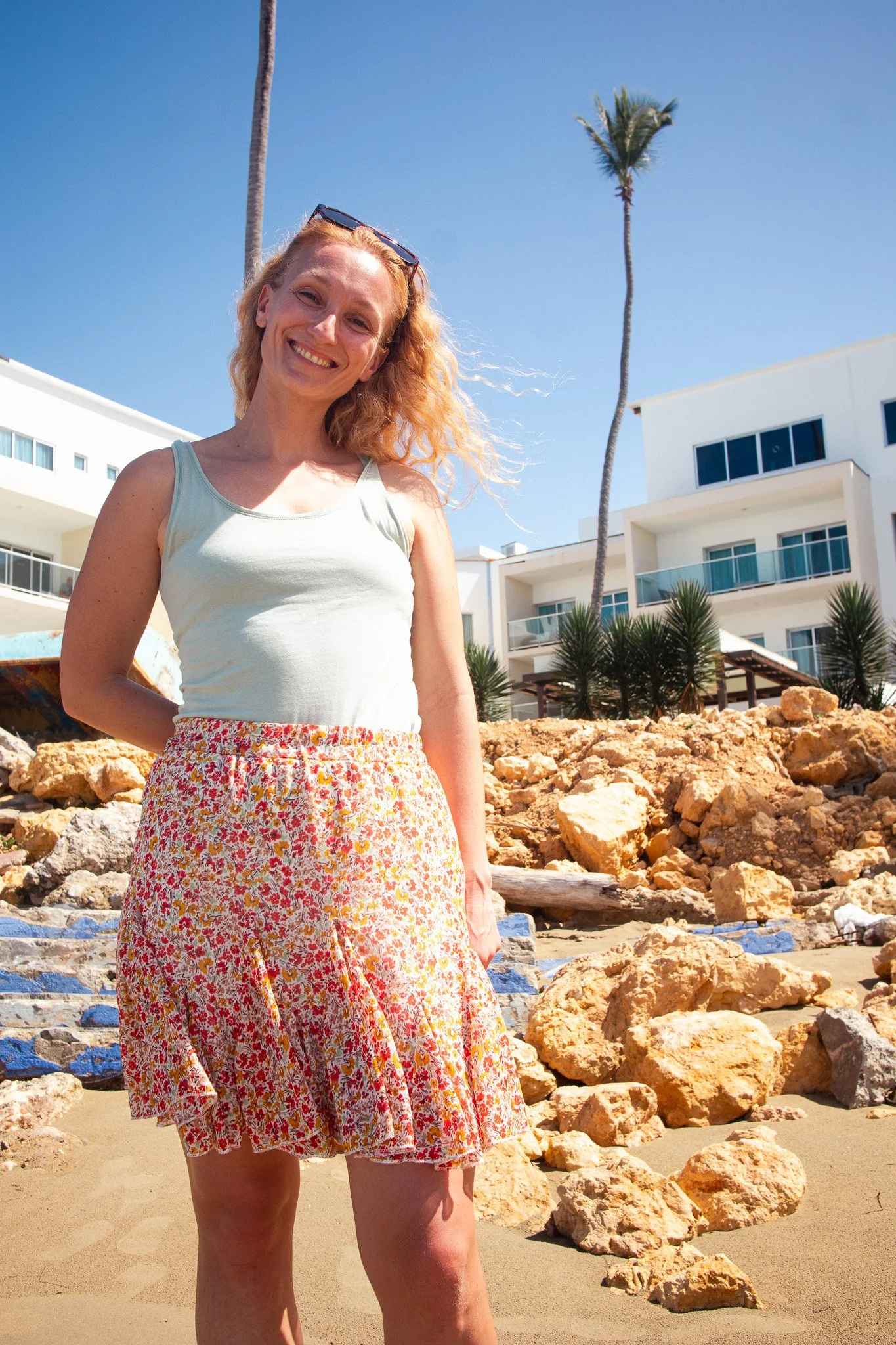 Woman smiling in front of a white hotel and palm trees