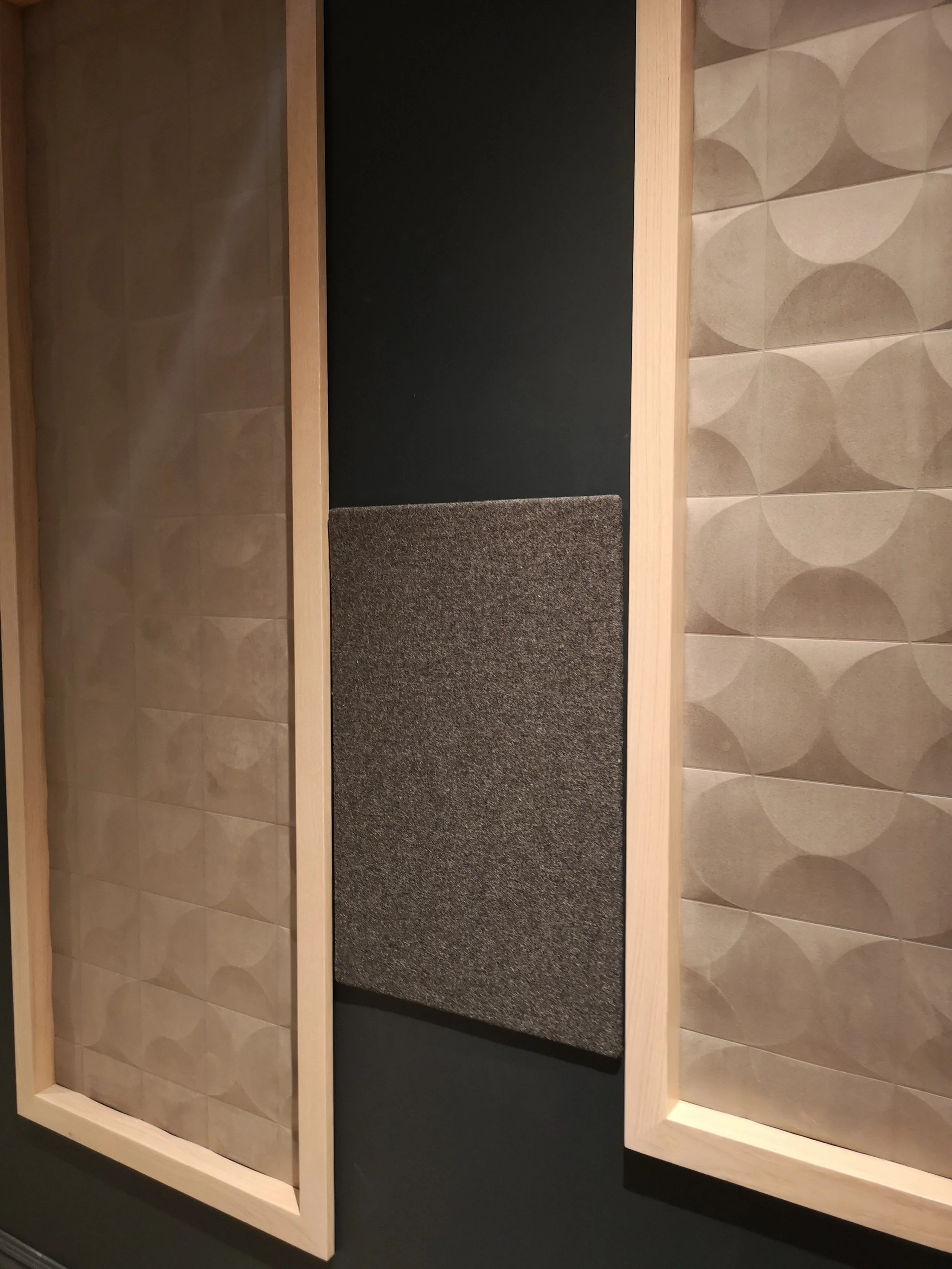 Two framed acoustic panels with textured, patterned surfaces on a dark wall