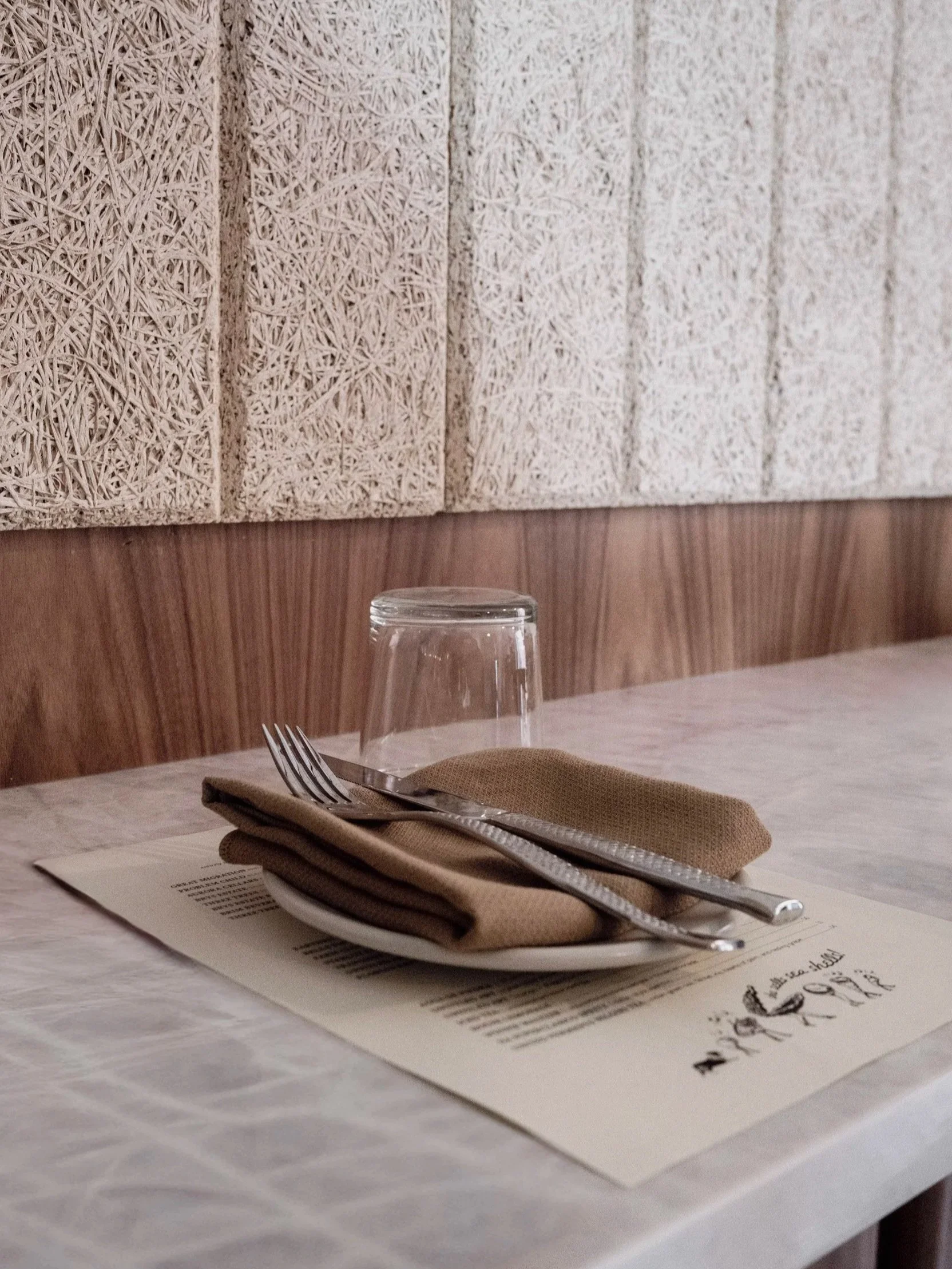 plate setting with menu on stone counter with warm wood and acoustic panels