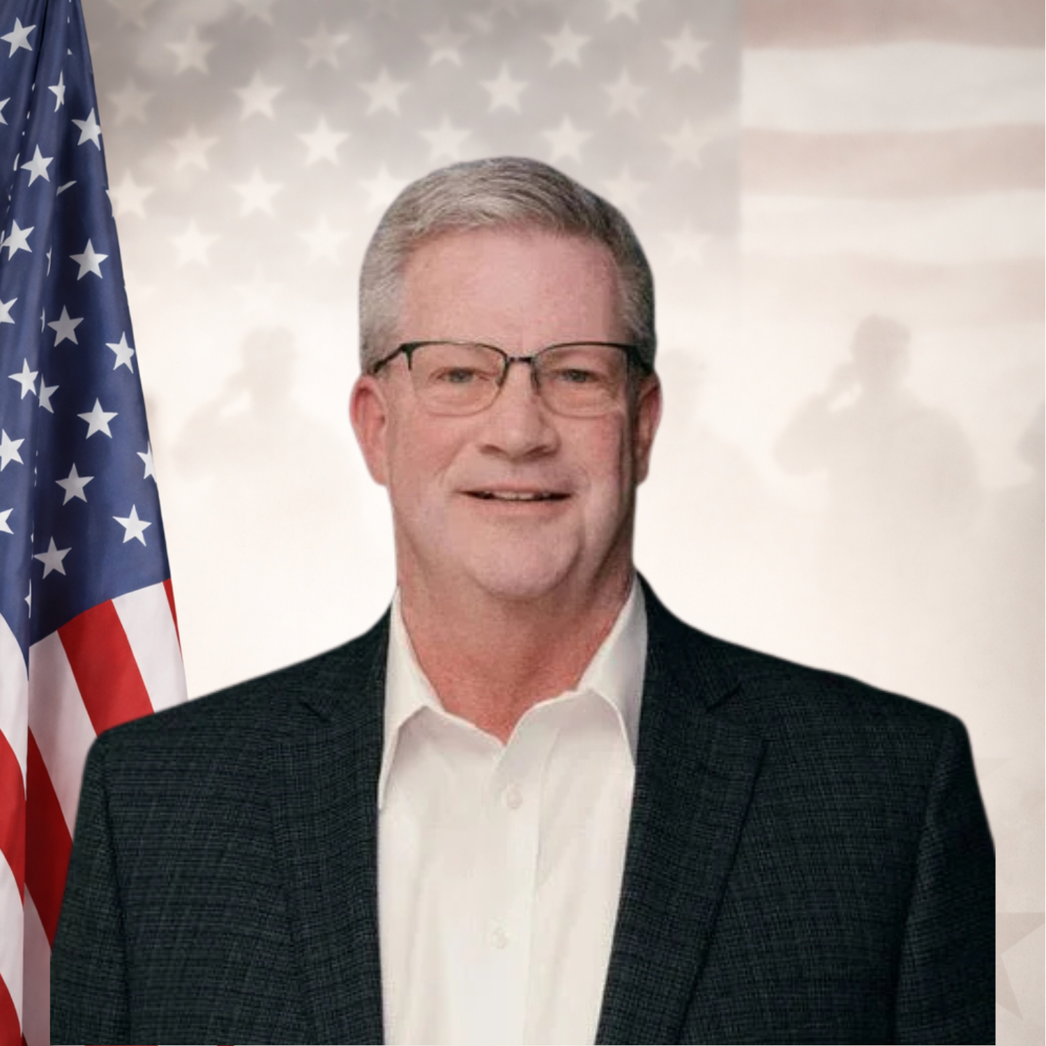 Portrait of a man in a gray suit with a pastel plaid tie, smiling in an indoor setting.