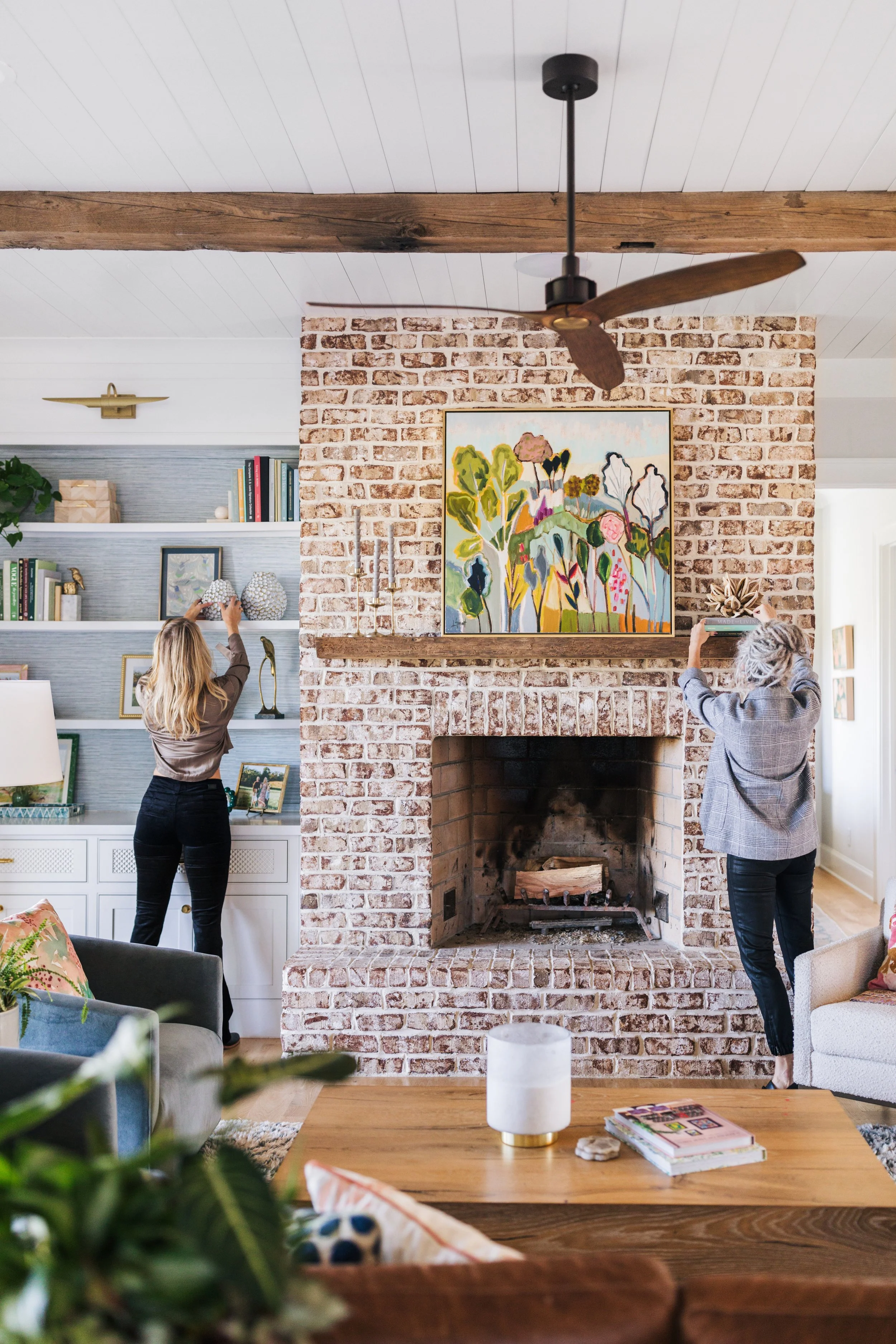 Beautiful living room with pink arm chair and gold lamp with brick fireplace