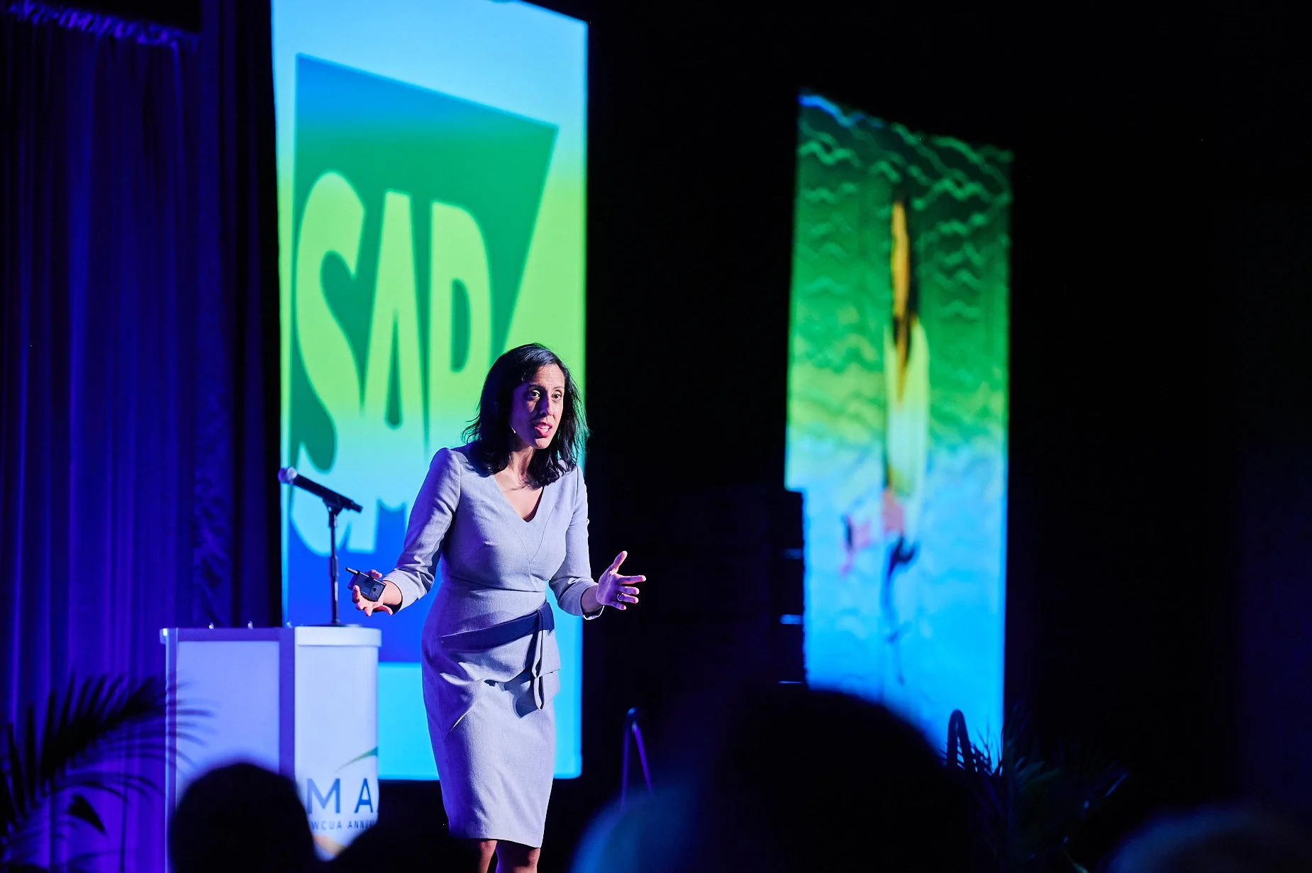 Woman speaking on stage with SAP logo in background
