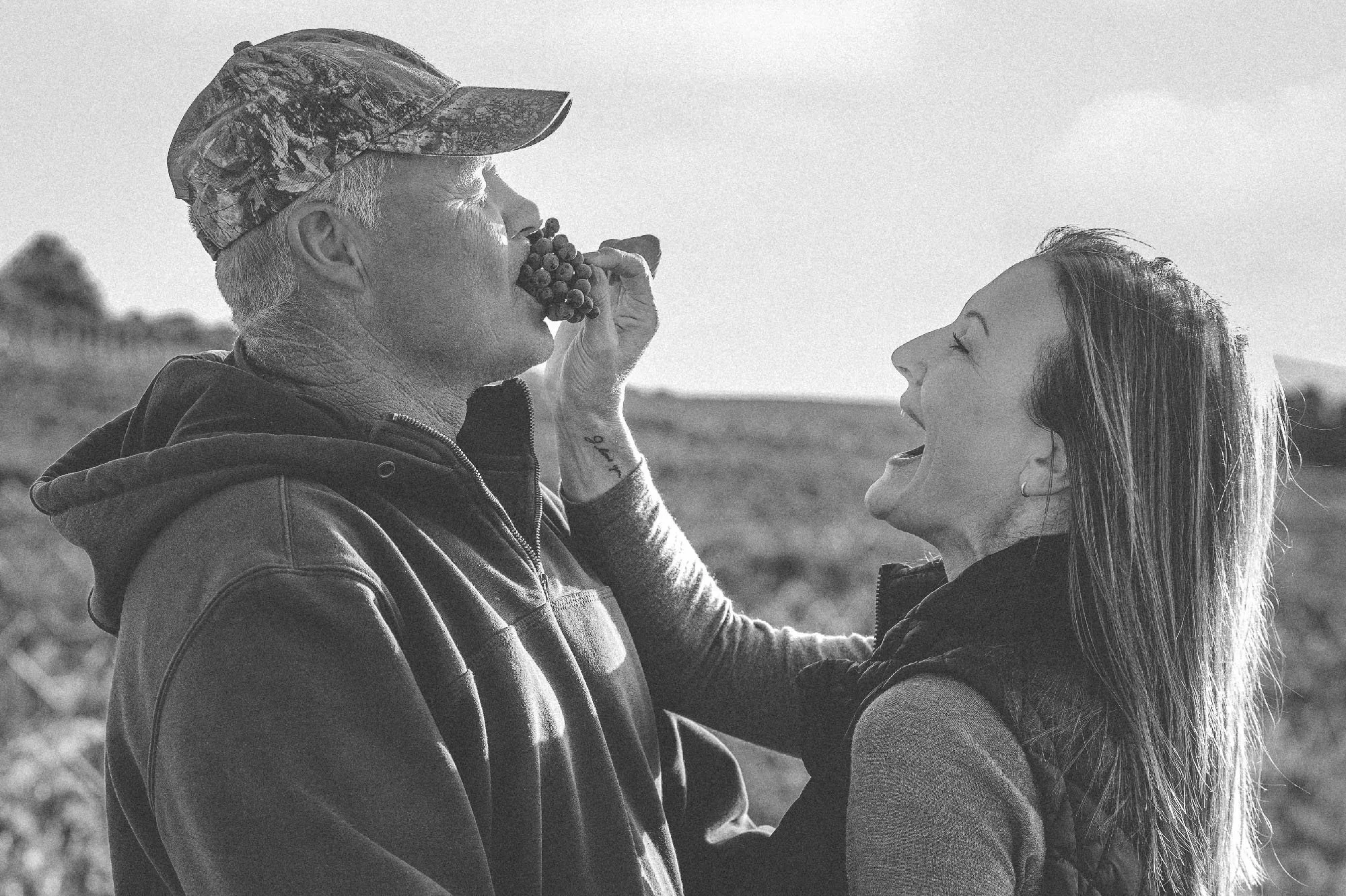 Black and white photo of a couple sharing a moment in the vineyard during harvest