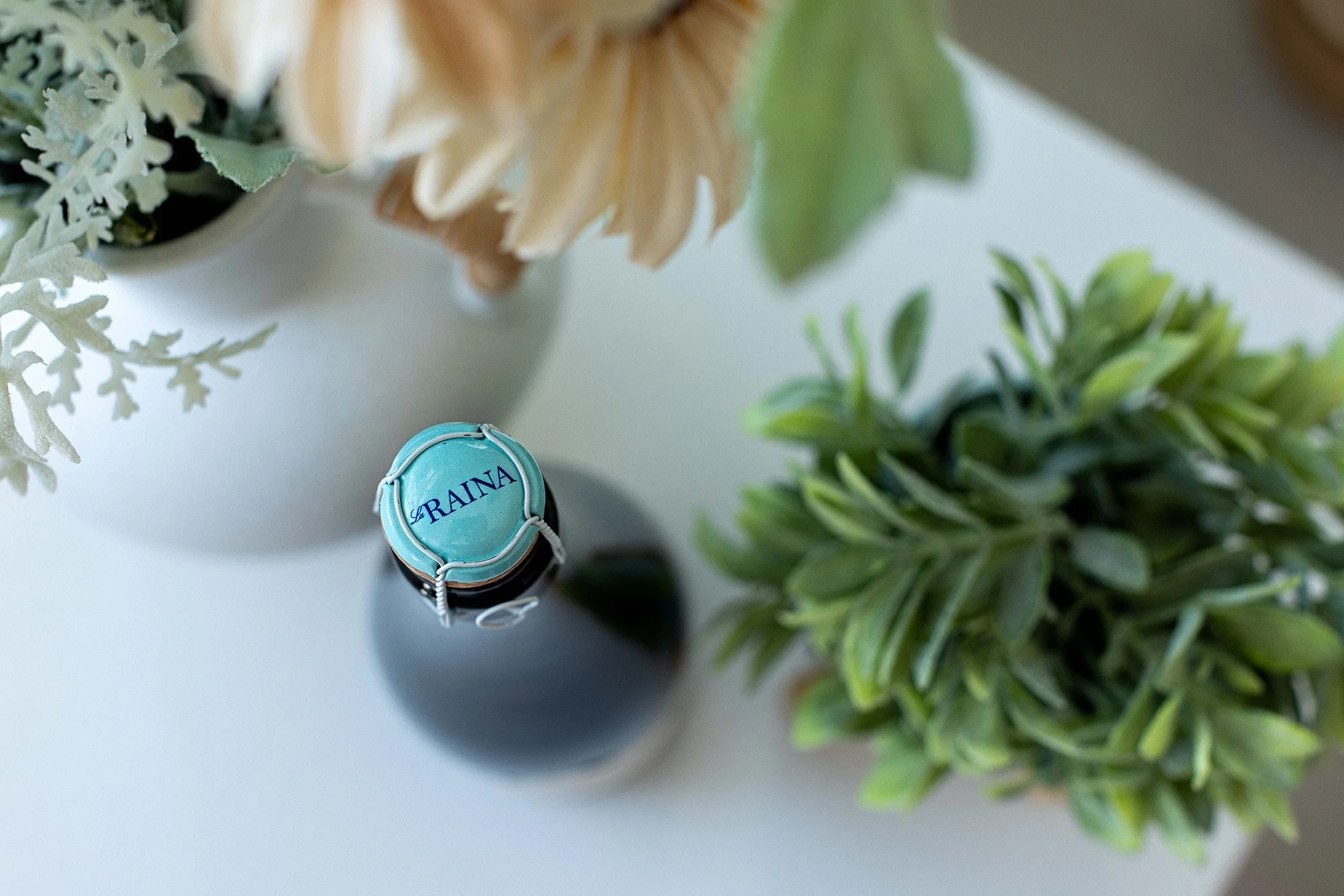 Close-up of a sparkling white wine bottle cap with floral styling, label design by Via Visual
