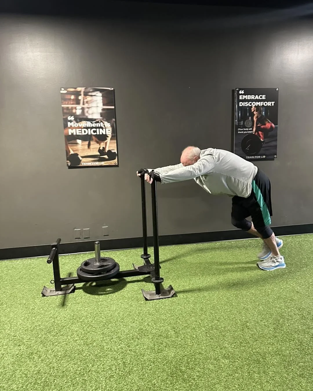 Older adult performing a weighted sled push during a functional strength training workout at FE Training & Nutrition in Creve Coeur, MO