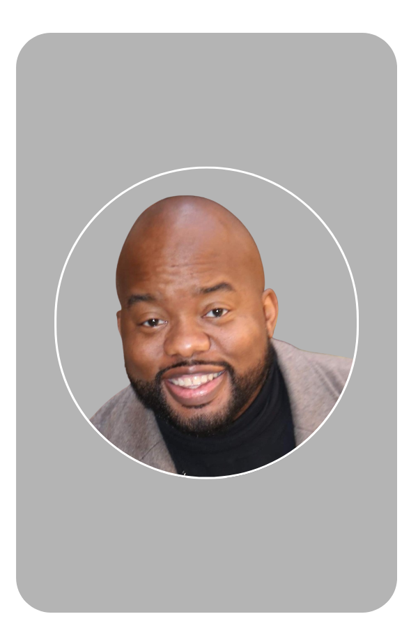 Smiling man with a beard and bald head wearing a coat and a black shirt on a black background.