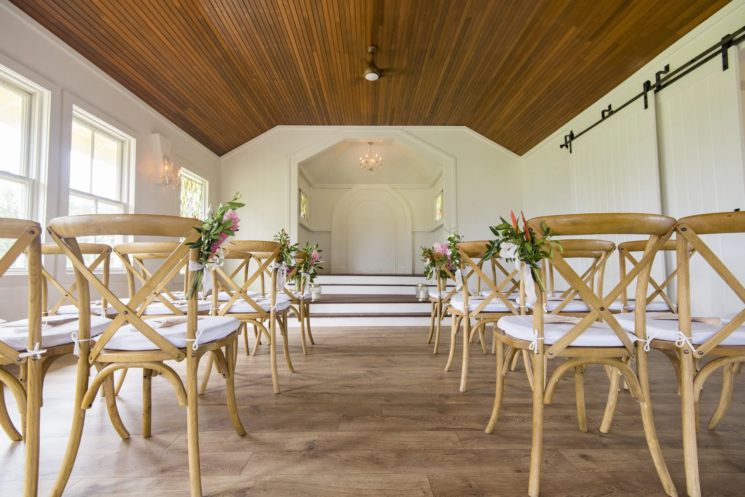 A wedding ceremony setup in a small chapel with warm wooden fixtures and white walls.
