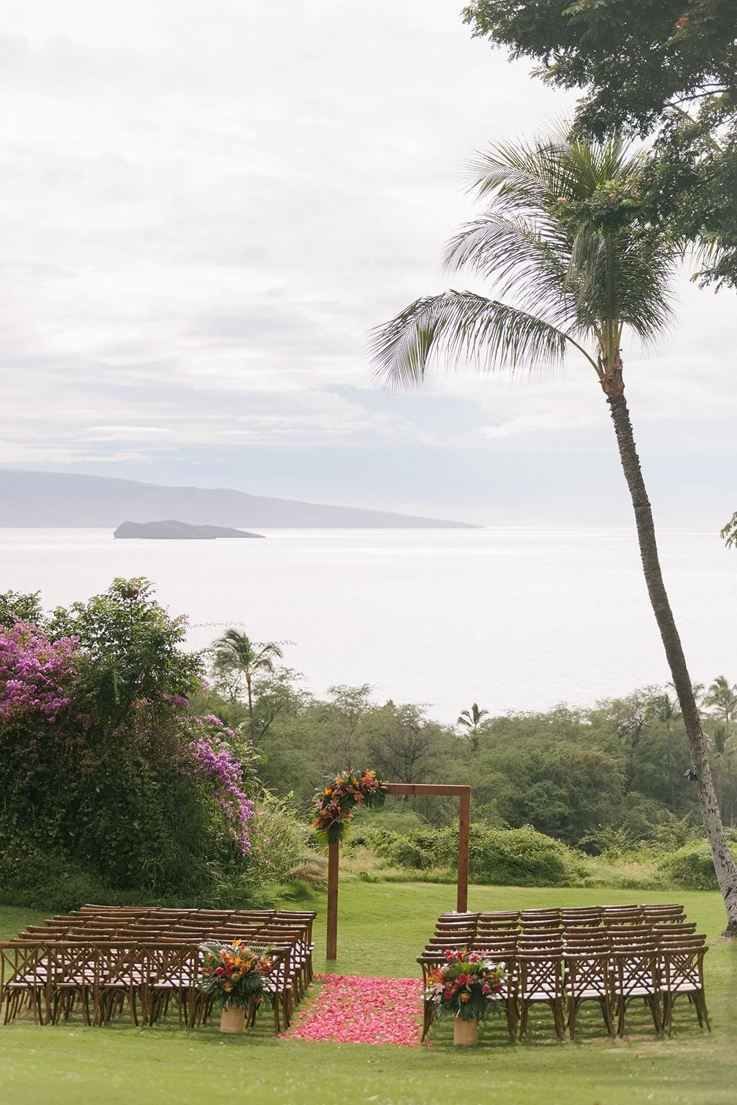 A tropical wedding ceremony setup with the ocean and Hawaiian islands in the distance
